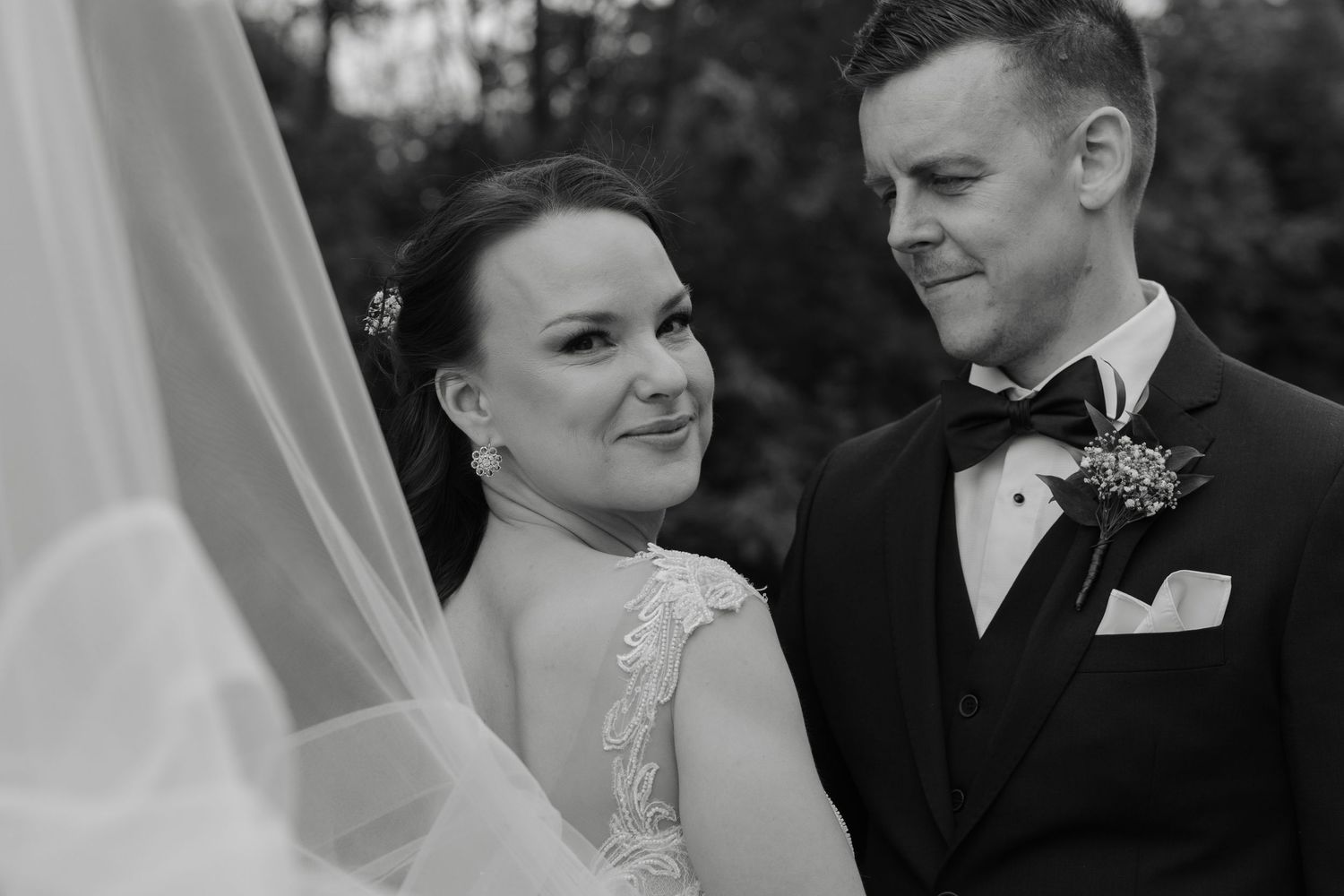 Black and white portrait of newlywed couple sharing intimate moment outdoors.