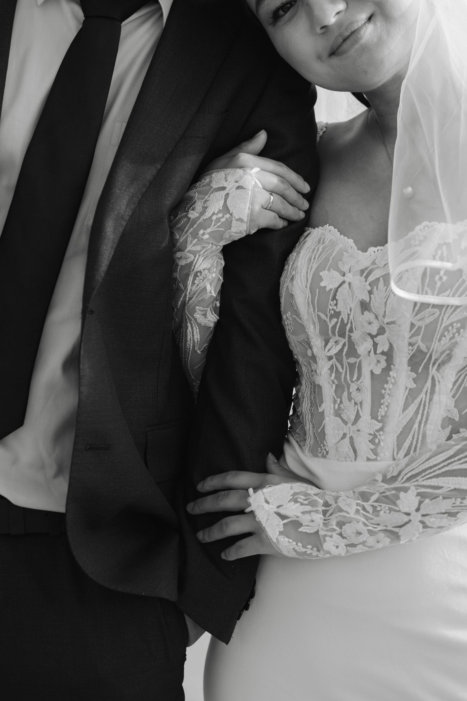 Black and white close-up of wedding attire showing intricate lace details.