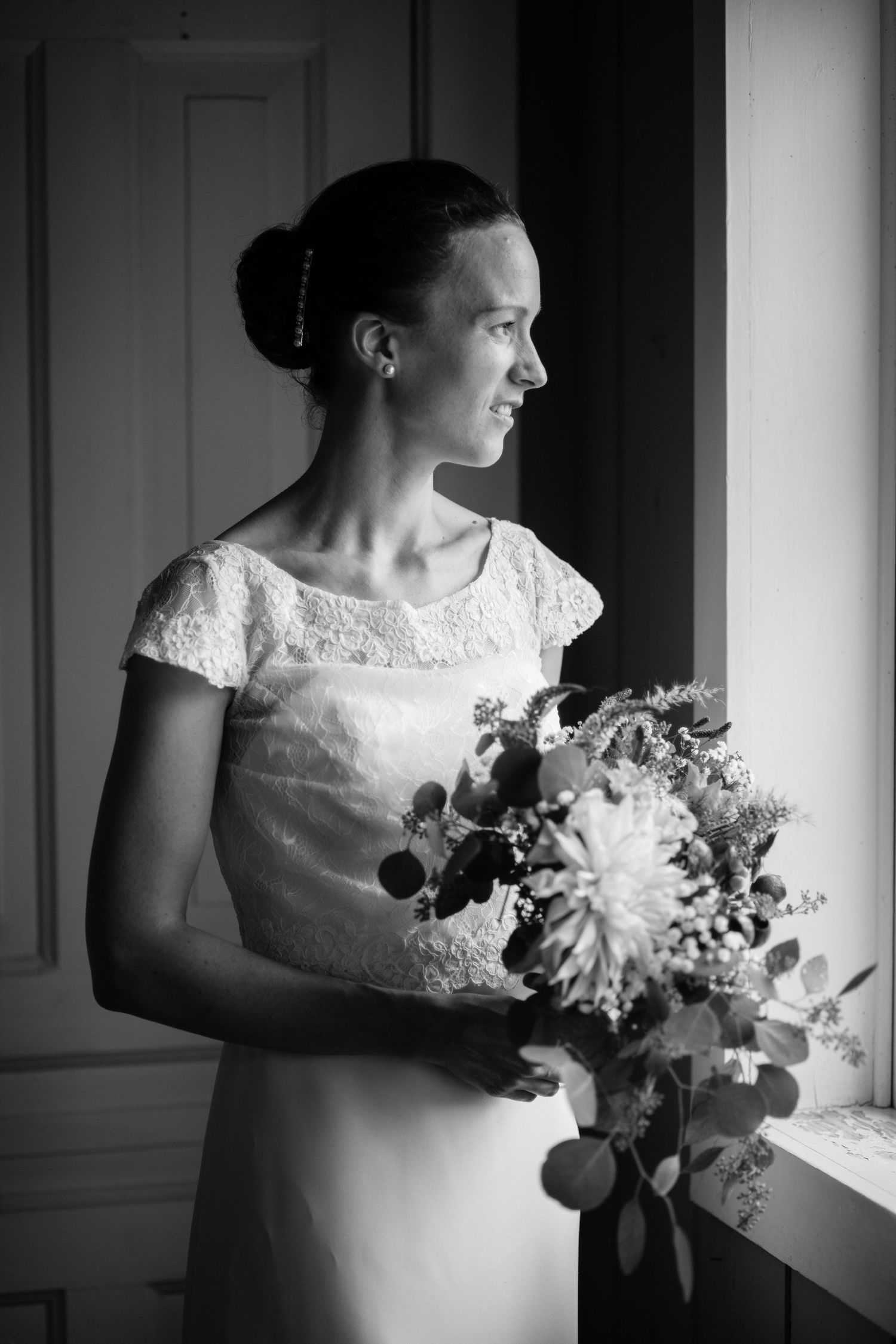 Artistic black and white series of bride holding bouquet by window.
