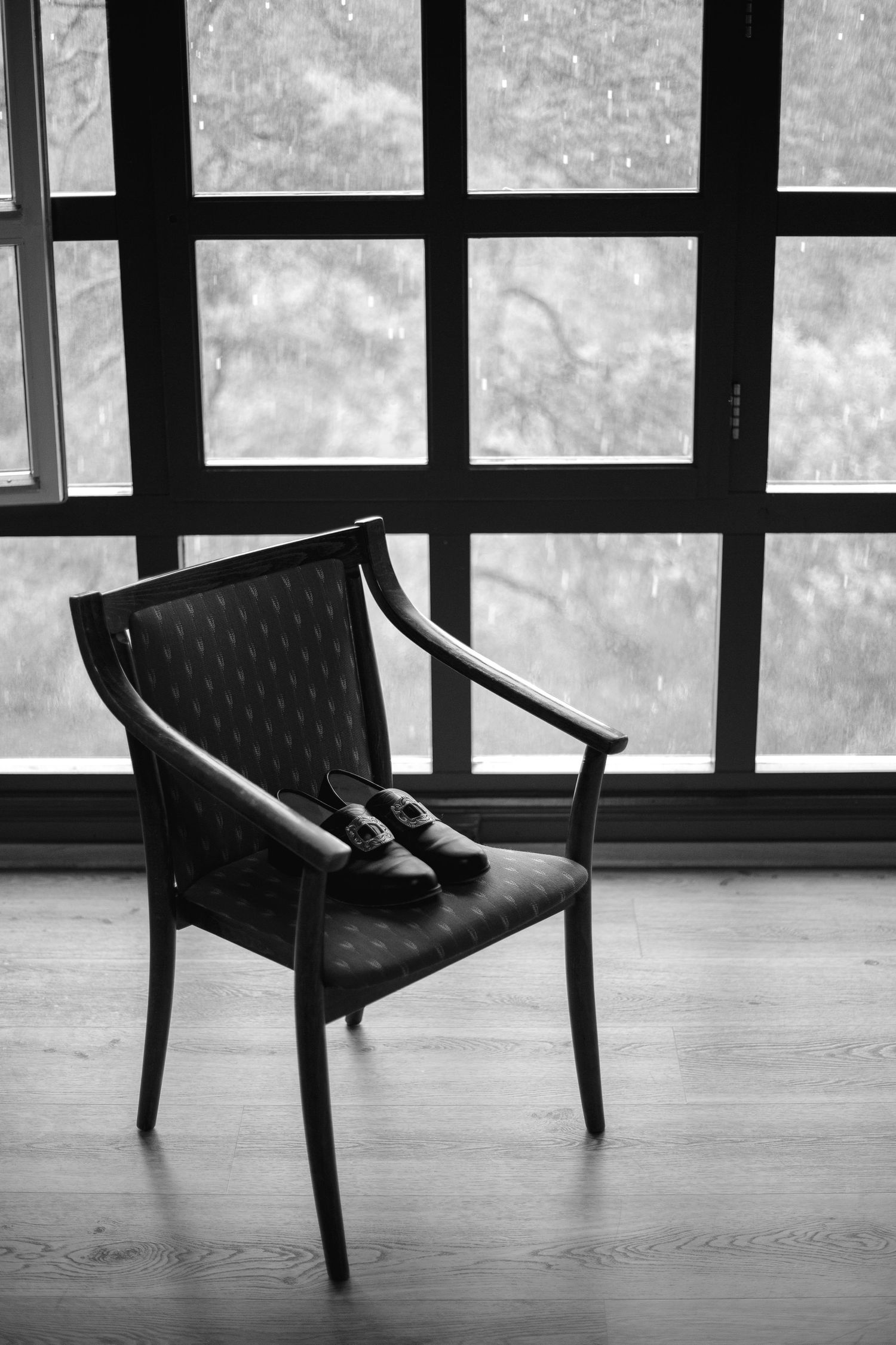 Black and white image of modern chairs arranged in a minimalist interior space with large windows.