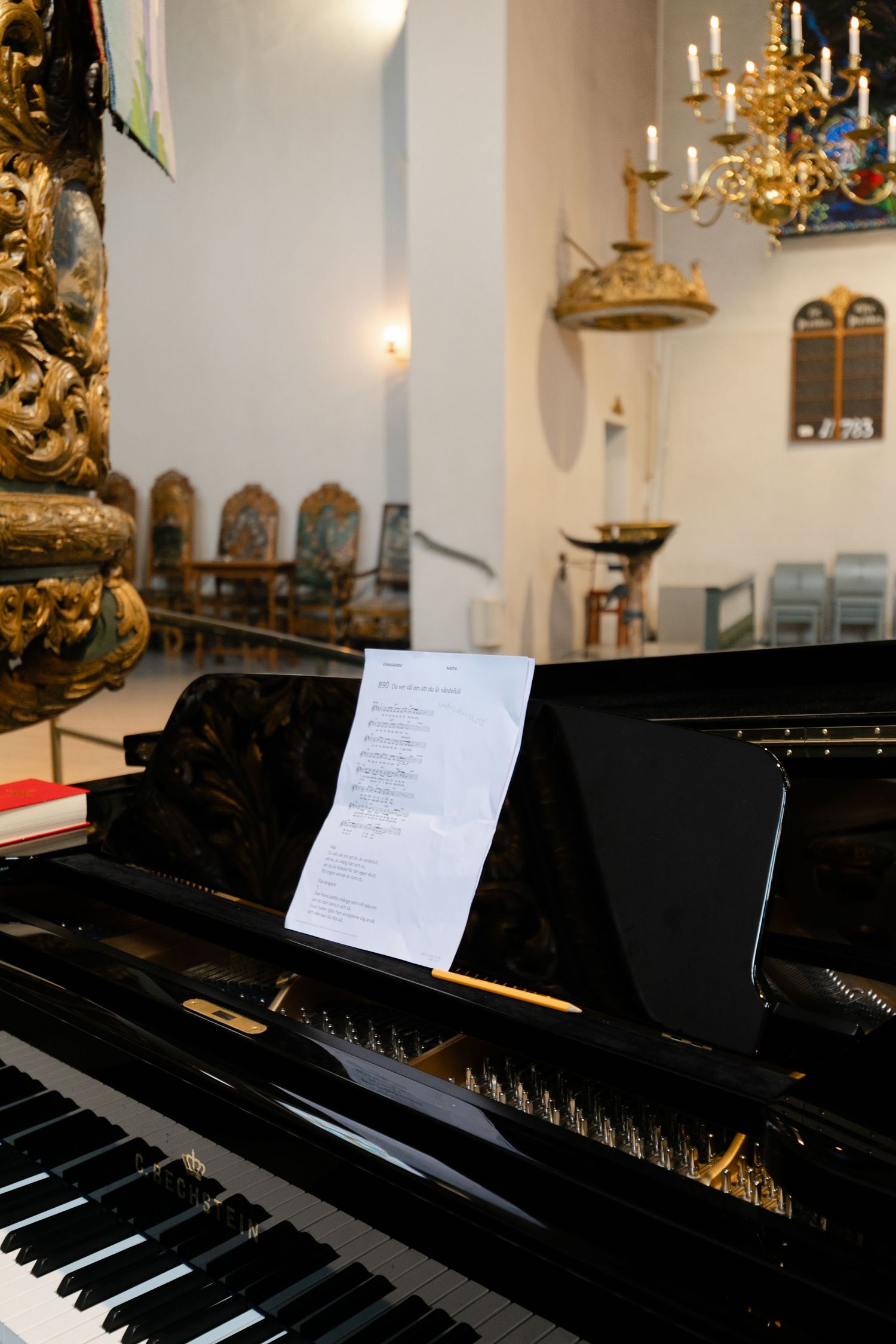 Grand piano with sheet music in an ornate church interior.