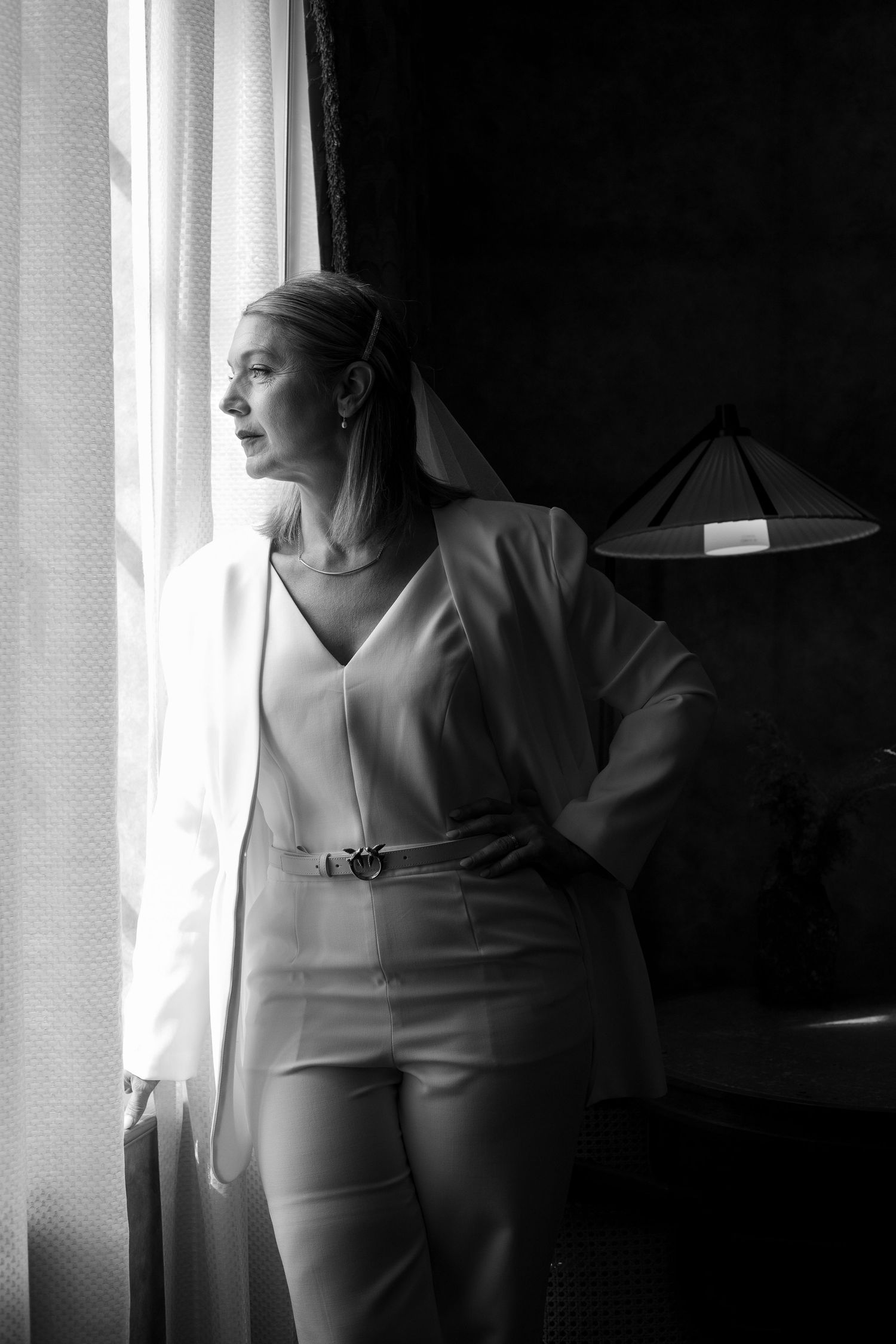 Dramatic black and white portrait showing a figure near a window with soft natural light.