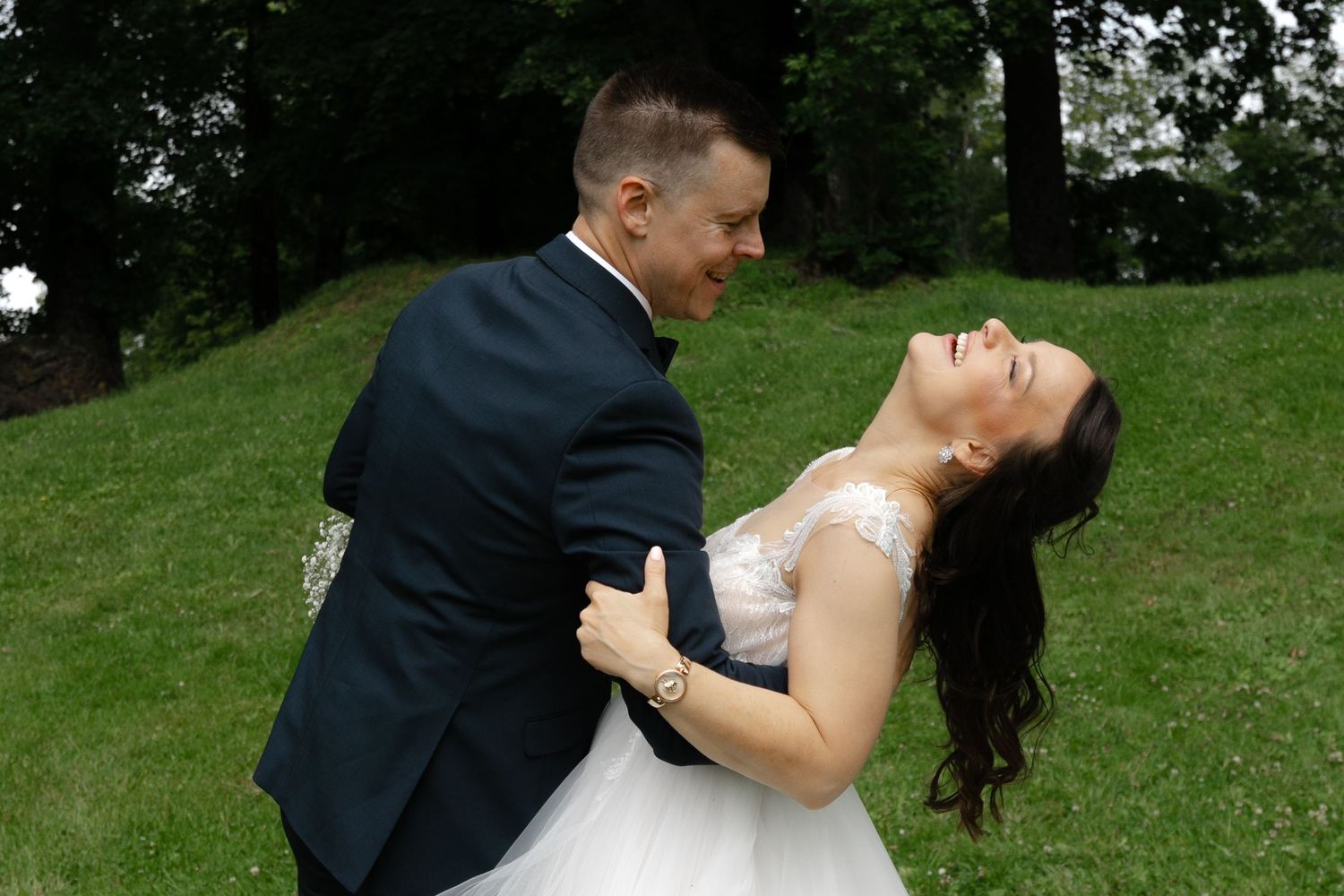 Romantic moment captured between newlyweds on a grassy hill.