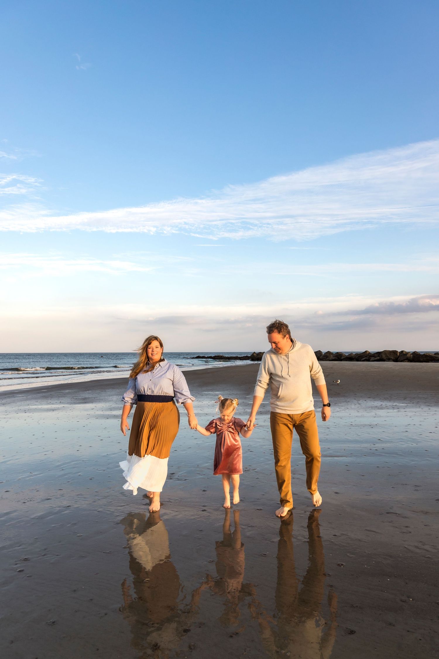 A family walks together on a beach at sunset, holding hands and enjoying the peaceful moment.