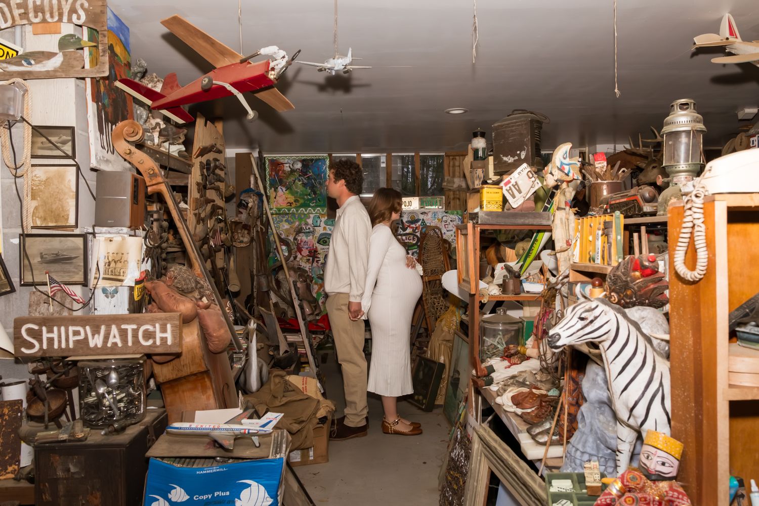Cluttered antique store interior displays vintage collectibles, furniture, and memorabilia on shelves and walls.