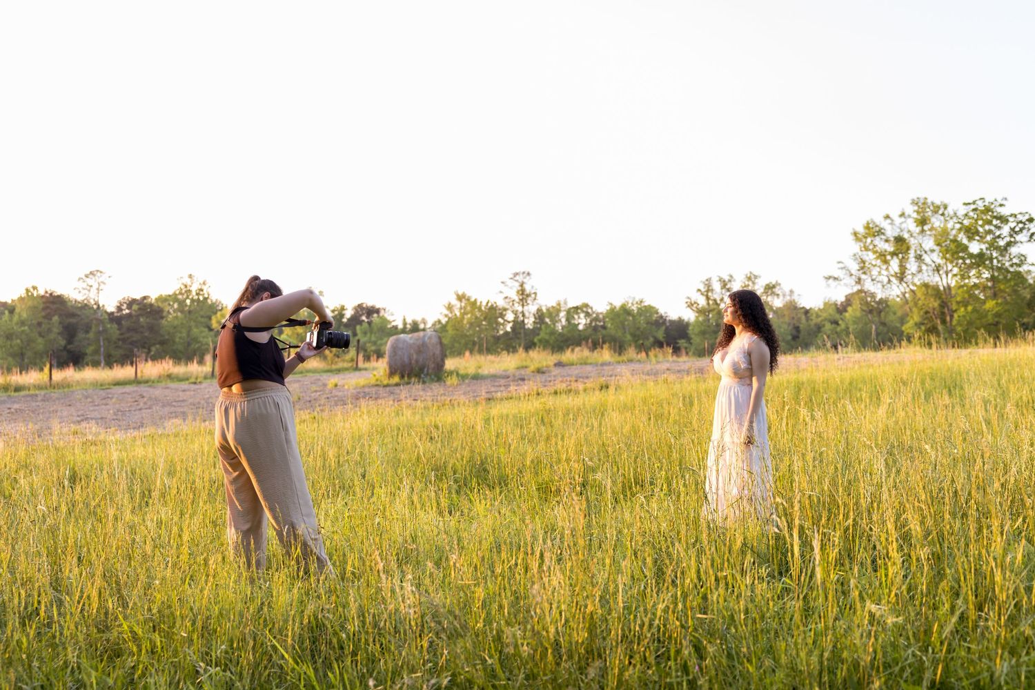 Couple embracing in a golden field during sunset as photographer captures their romantic engagement photos.