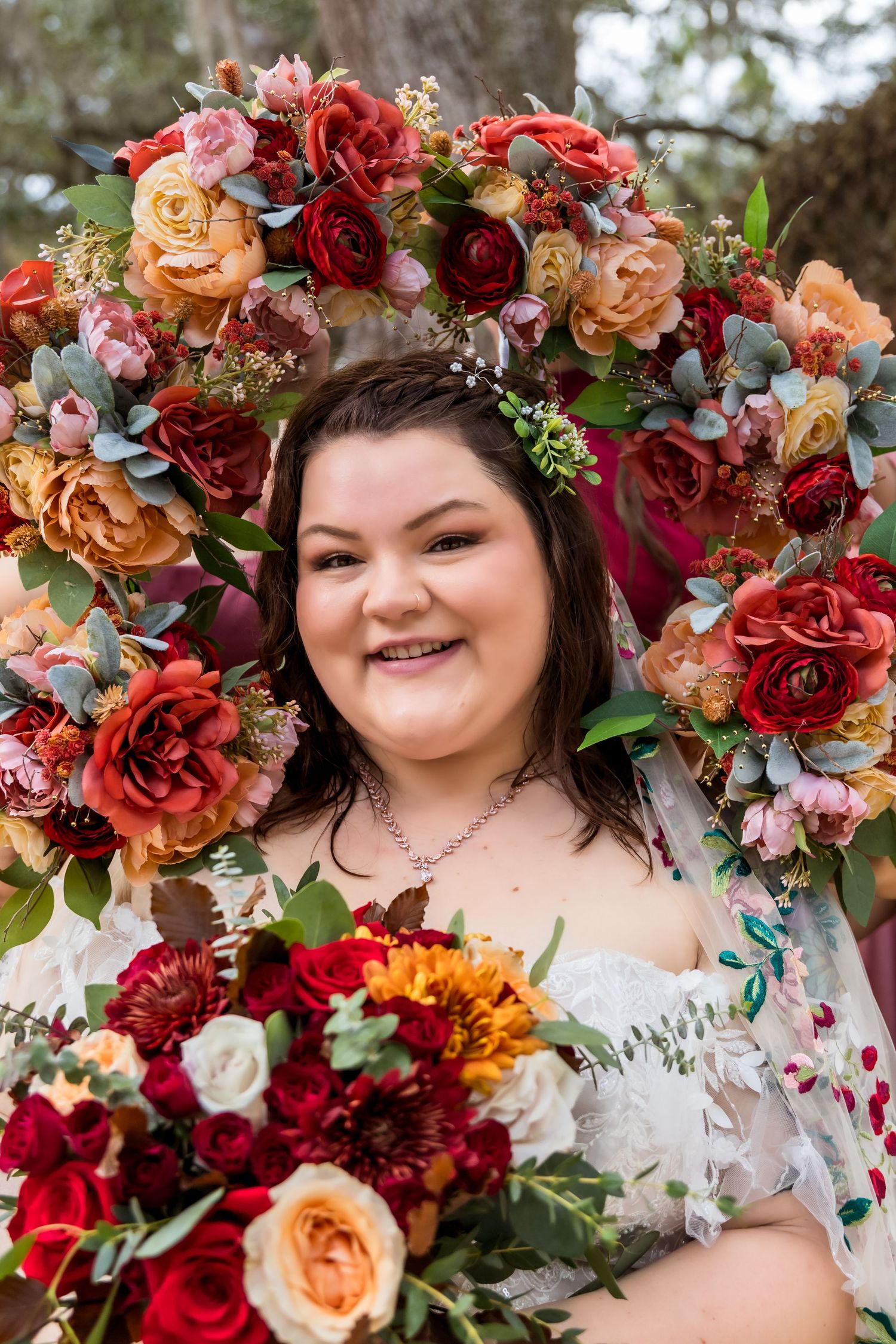 Beautiful floral crown with red and peach roses adorned with delicate greenery and small white flowers.