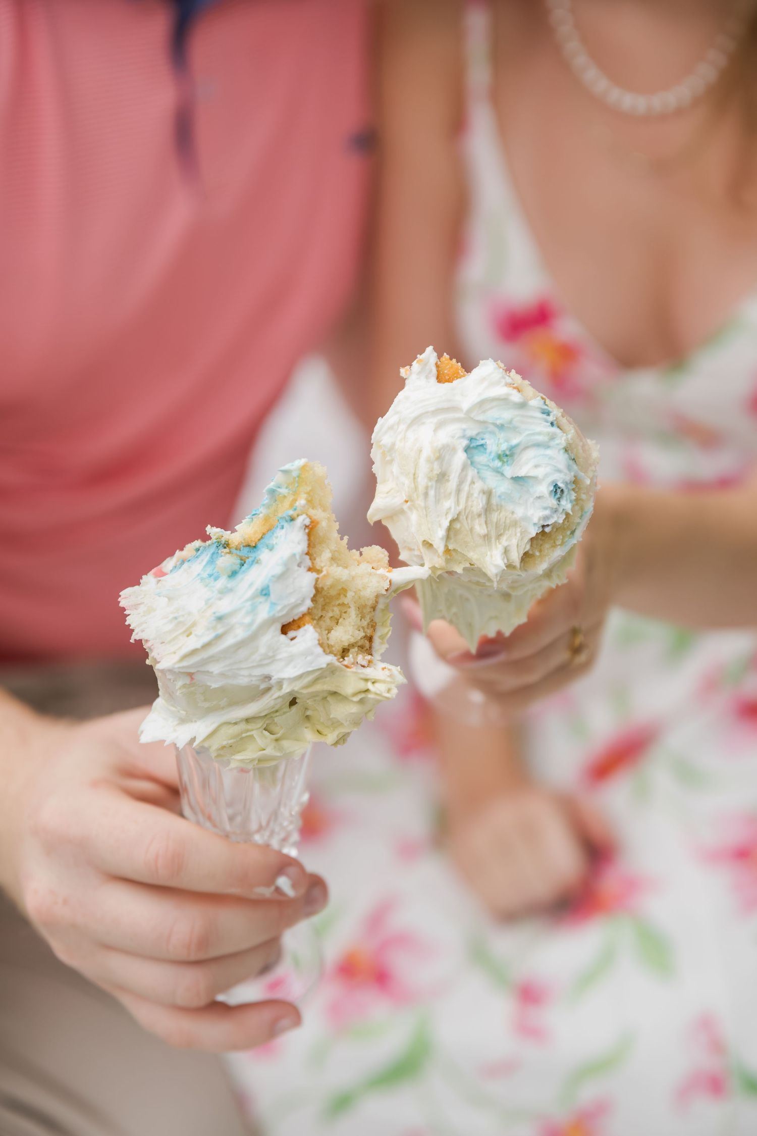 Couple holding two ice cream cones with white and blue swirled soft serve, wearing casual summer outfits.