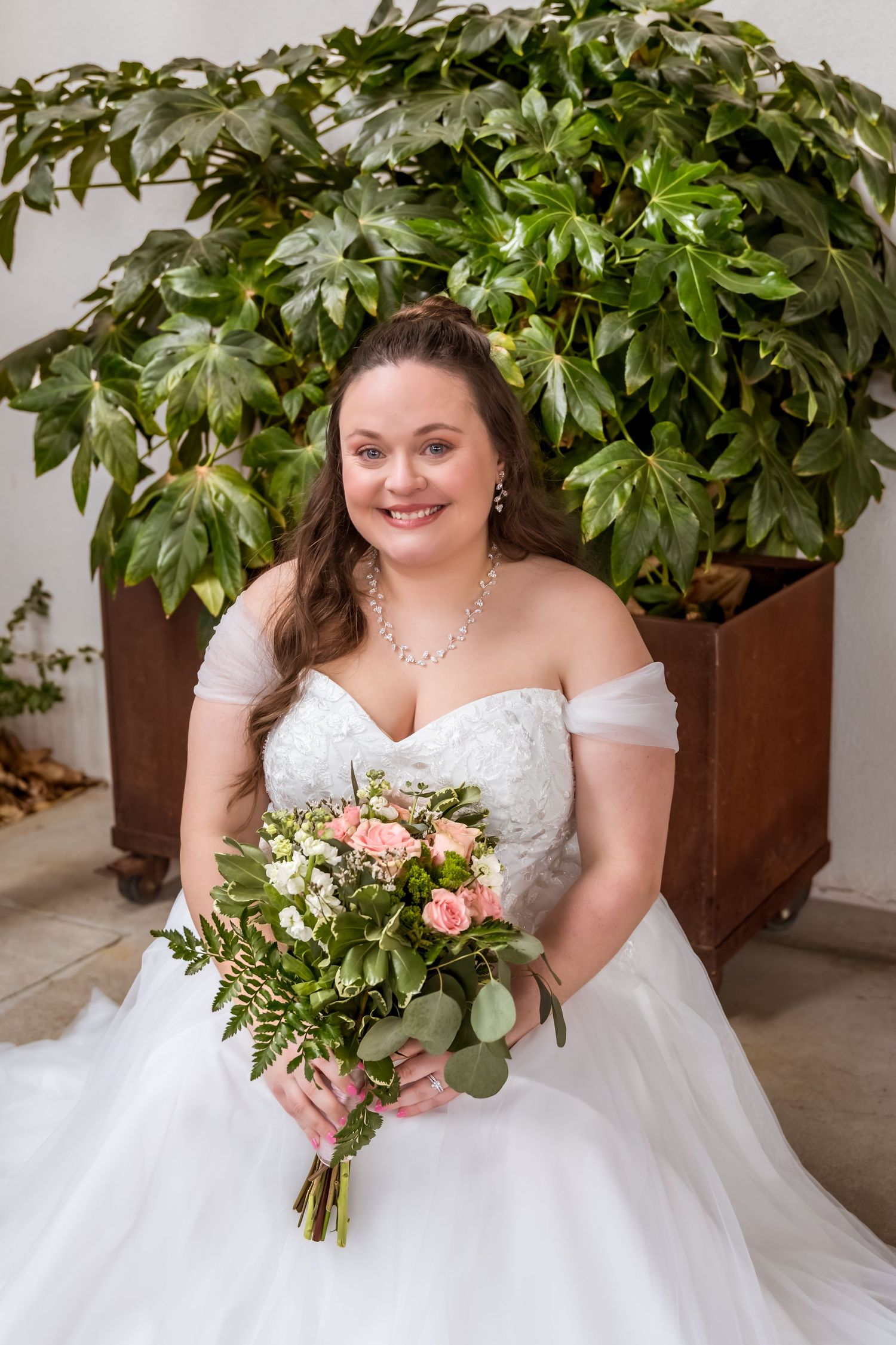 A bridal portrait series showing a white wedding dress against lush green foliage in decorative planters.