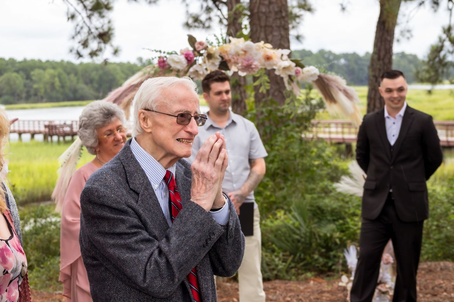 Wedding guests seated outdoors reacting emotionally during ceremony.