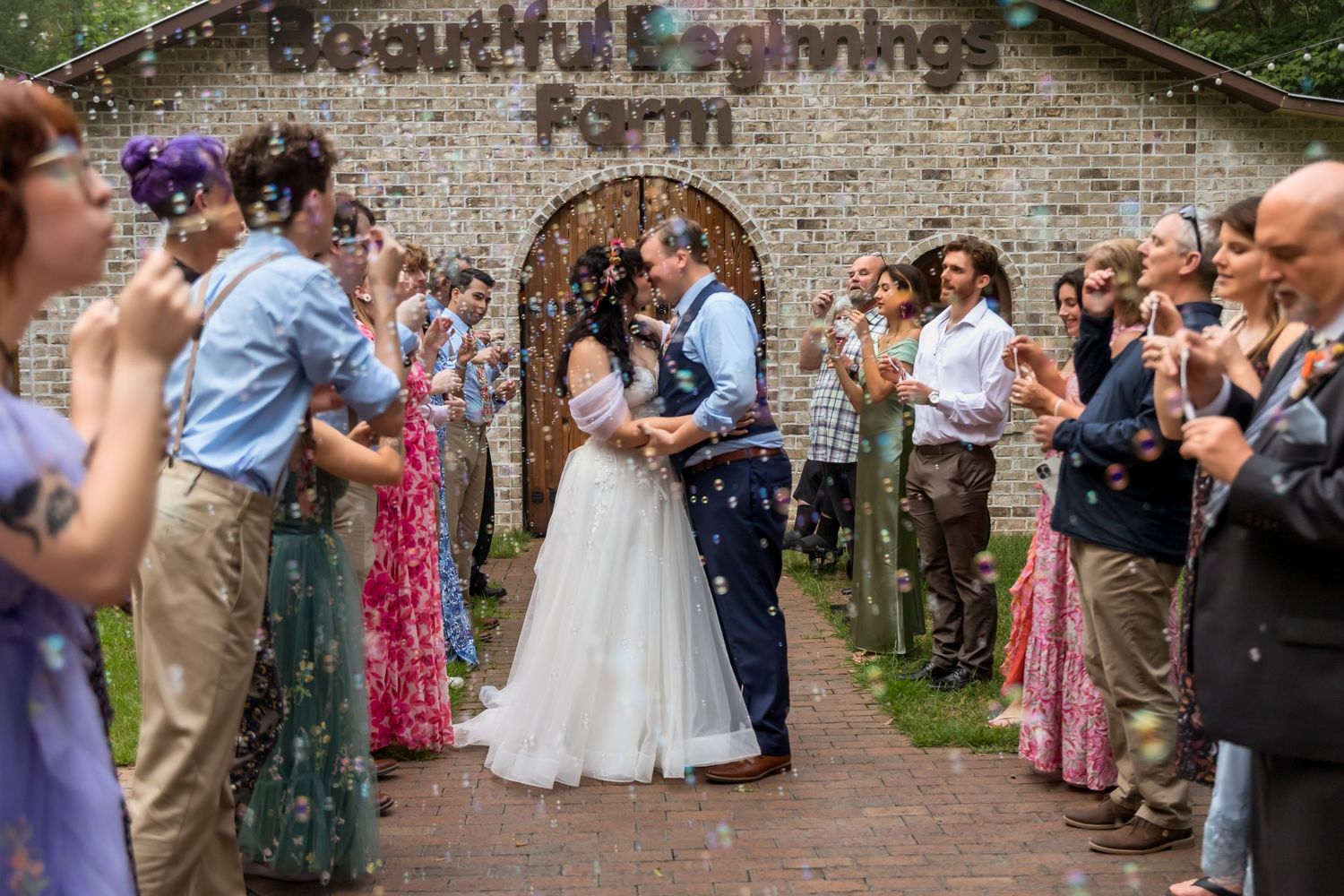 Wedding celebration with guests throwing confetti in a rustic brick-walled courtyard.