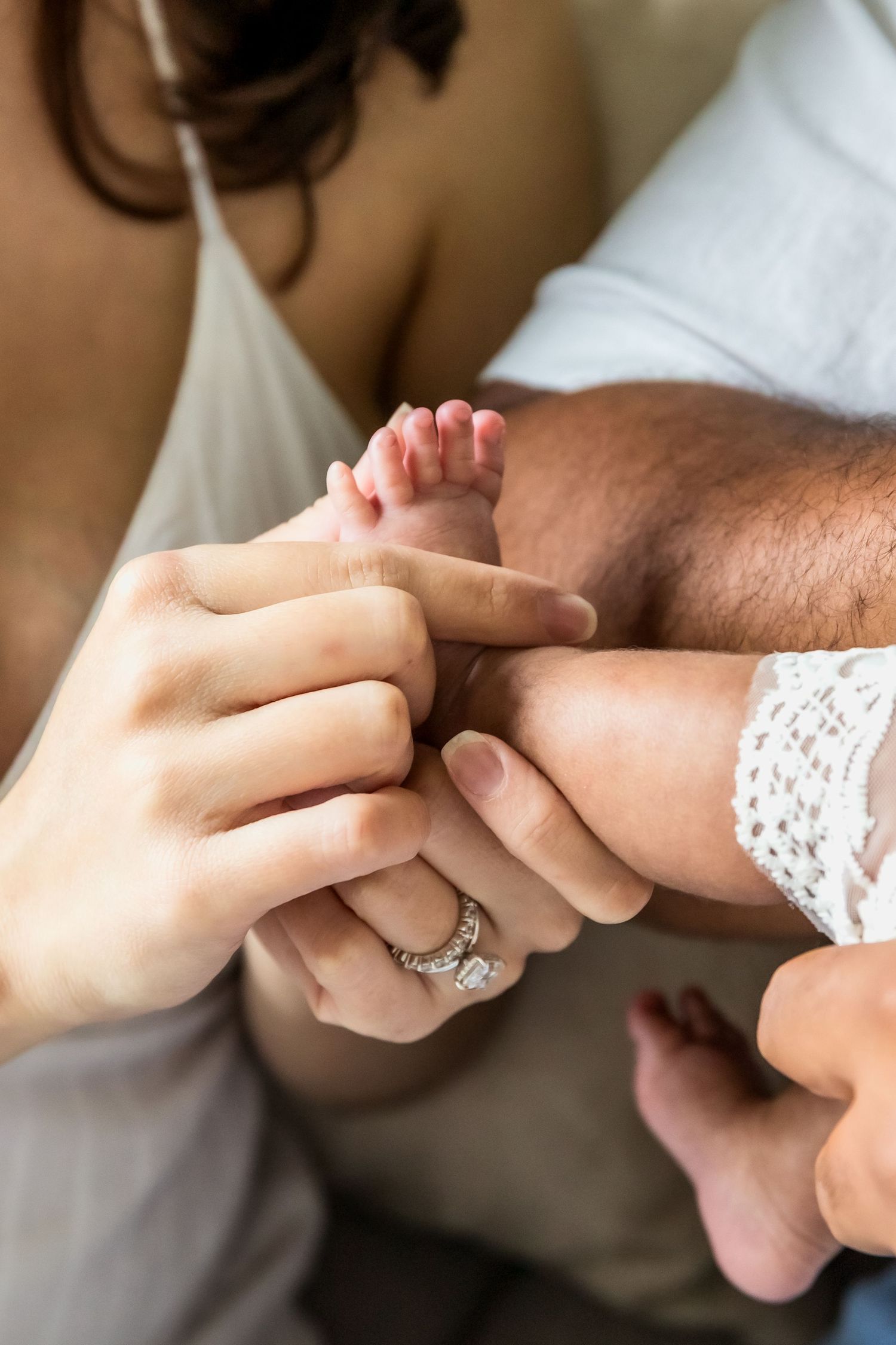 Close-up of hands with delicate lace detail and engagement ring showing wedding day details.