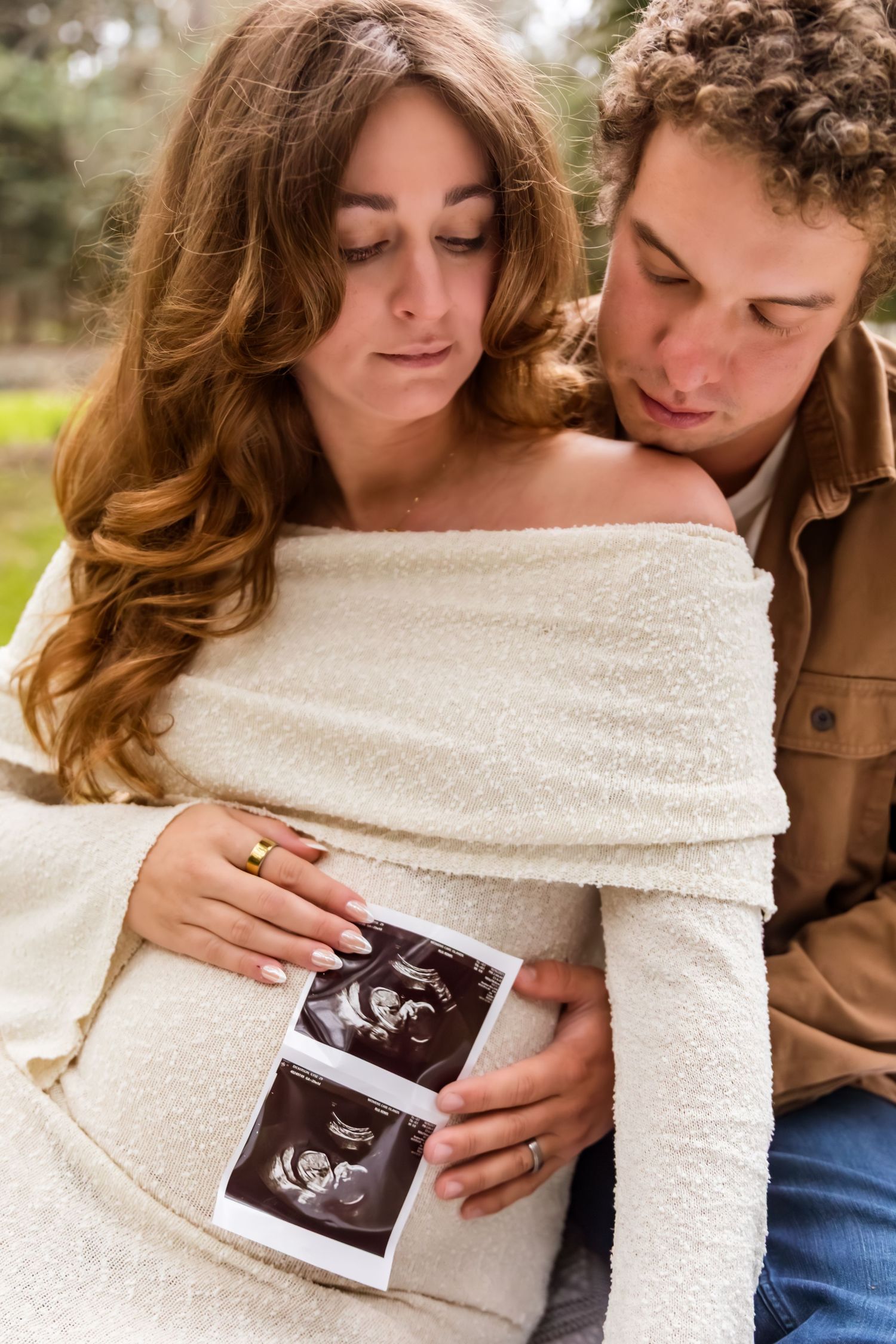 A couple holds a sonogram photo against a white sweater in a pregnancy announcement photo sequence.