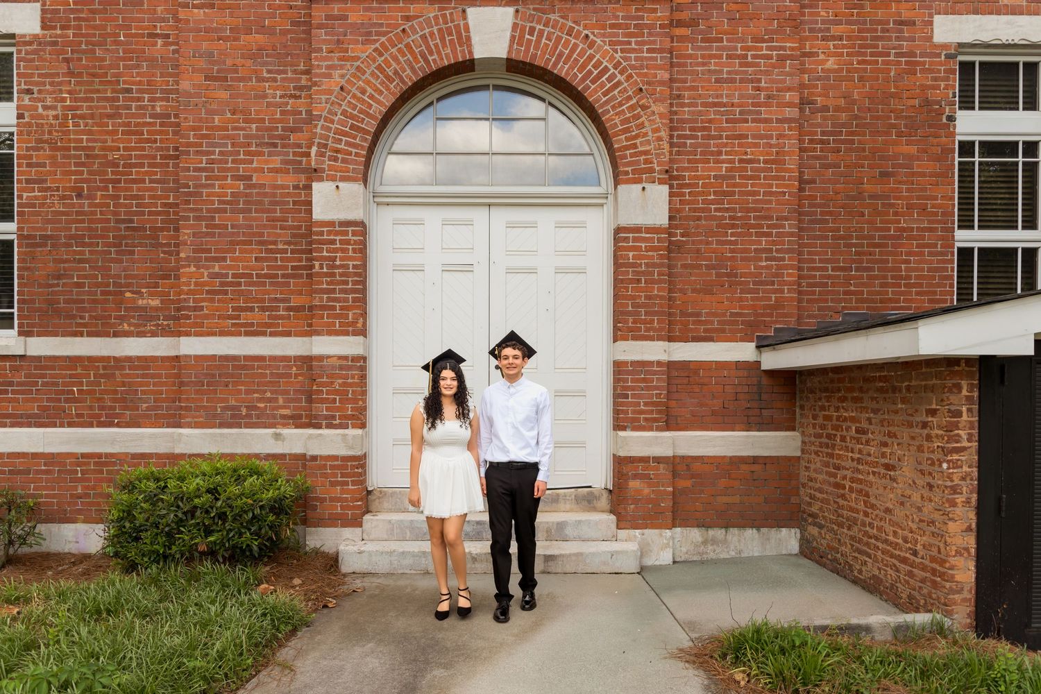 Red brick building entrance with white architectural details and arched doorway.