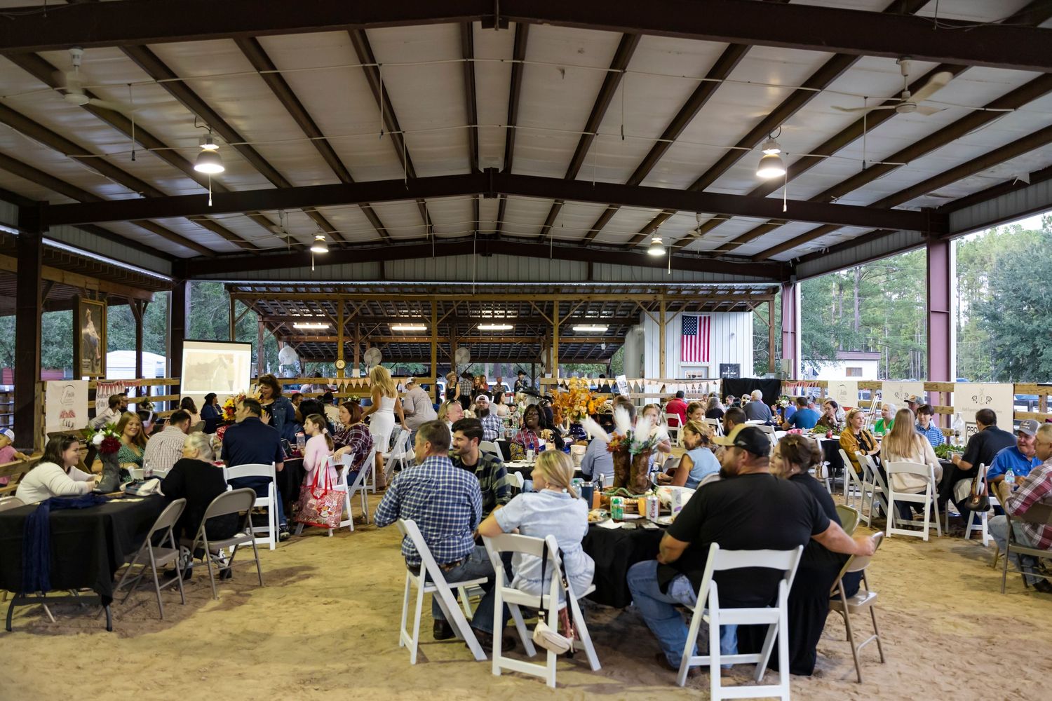 Large covered pavilion filled with people seated at tables for a community gathering.