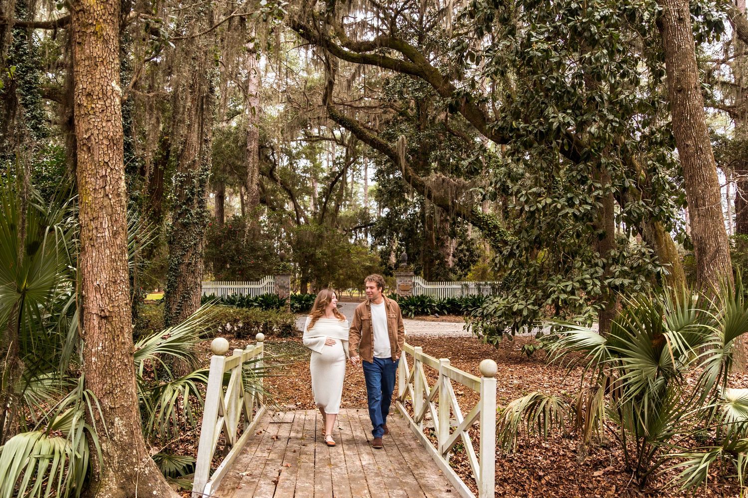 A wooden boardwalk path winds through a scenic wooded forest area with tall trees and natural landscaping.