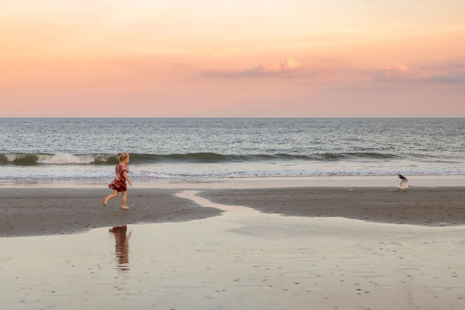 Peaceful beach scene at sunset with orange sky.