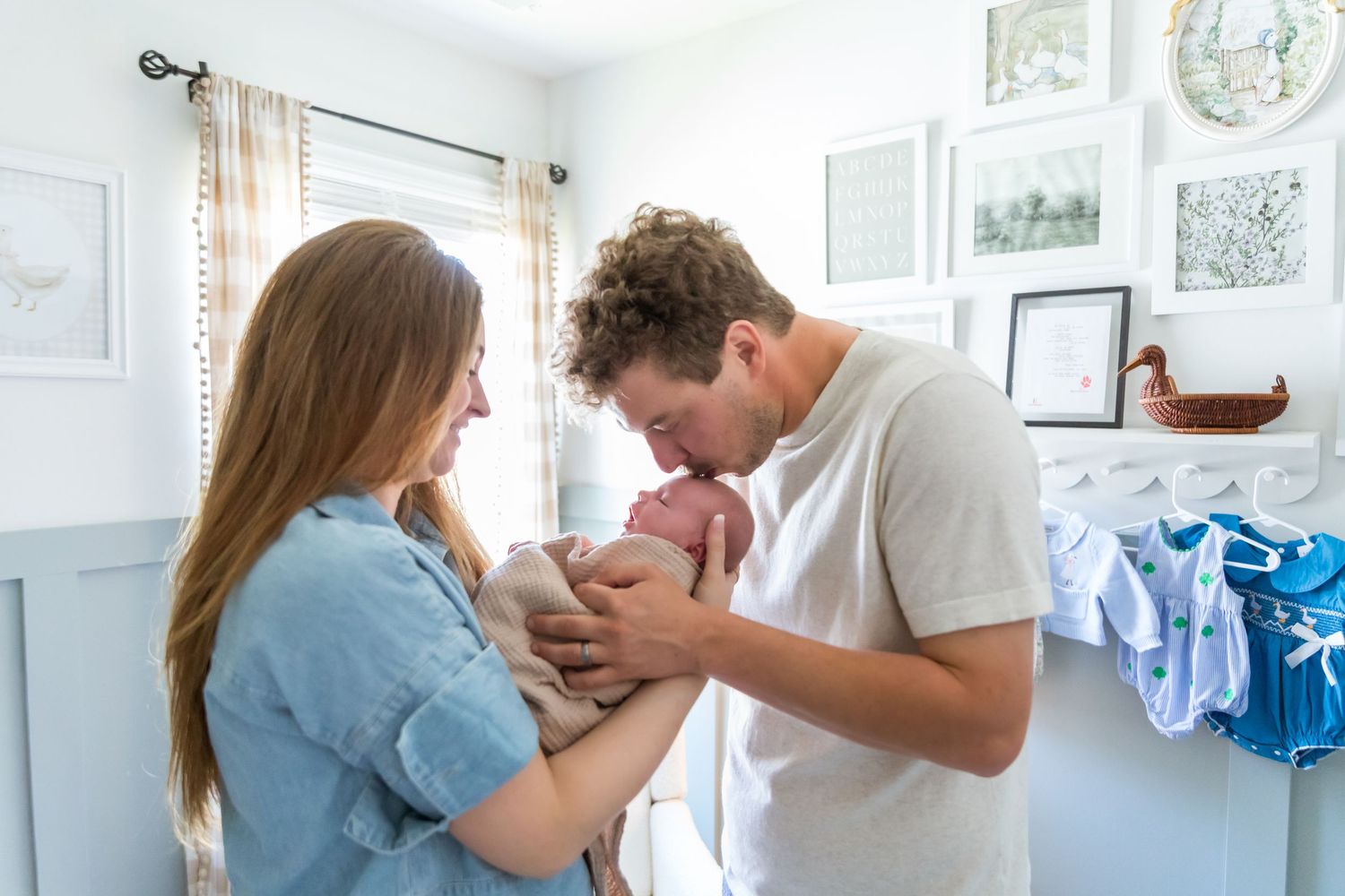 Young parents sharing a tender moment with their newborn baby in a softly decorated nursery room.