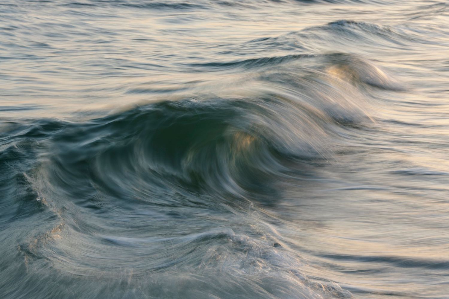 Gentle ocean waves roll across blue-green waters creating a mesmerizing pattern of ripples and movement.