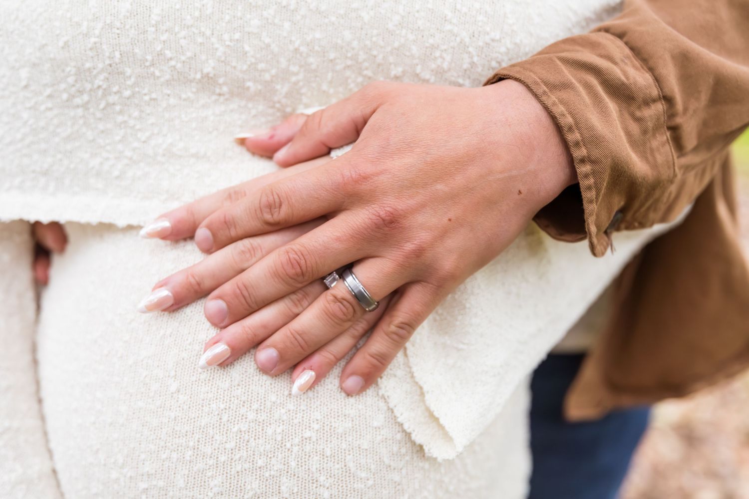 Close-up of hands wiping down a wooden surface with a white cleaning cloth.