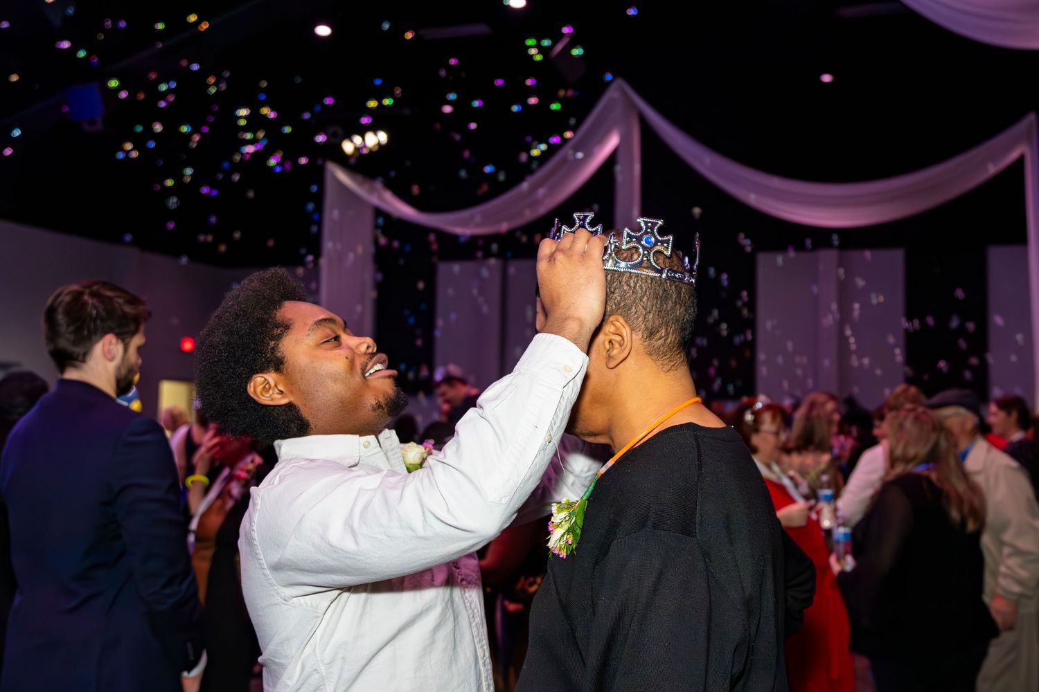 Indoor party scene with purple lighting and confetti falling from the ceiling.