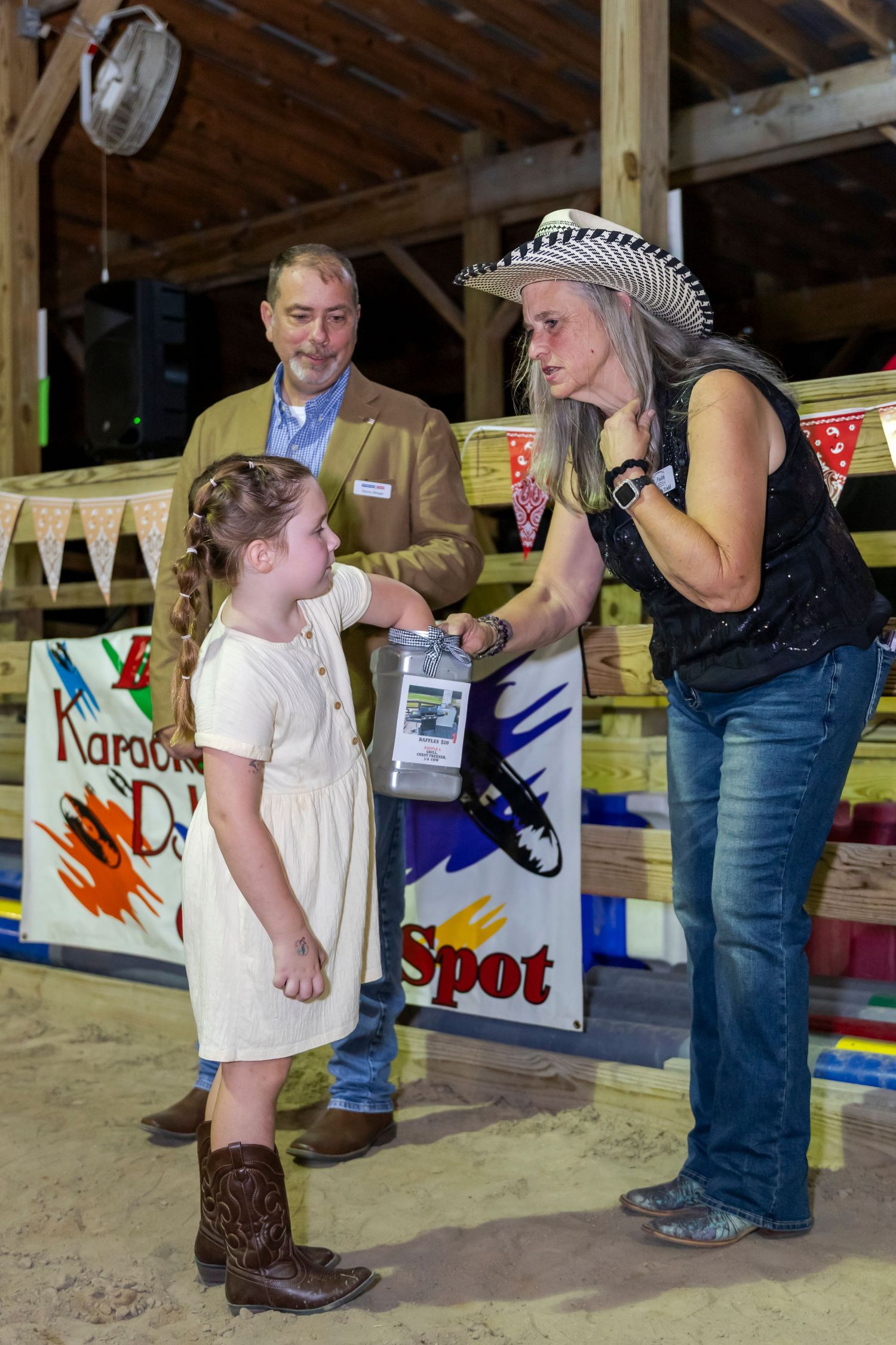 Children and adults interacting at a fairground booth with colorful decorations.