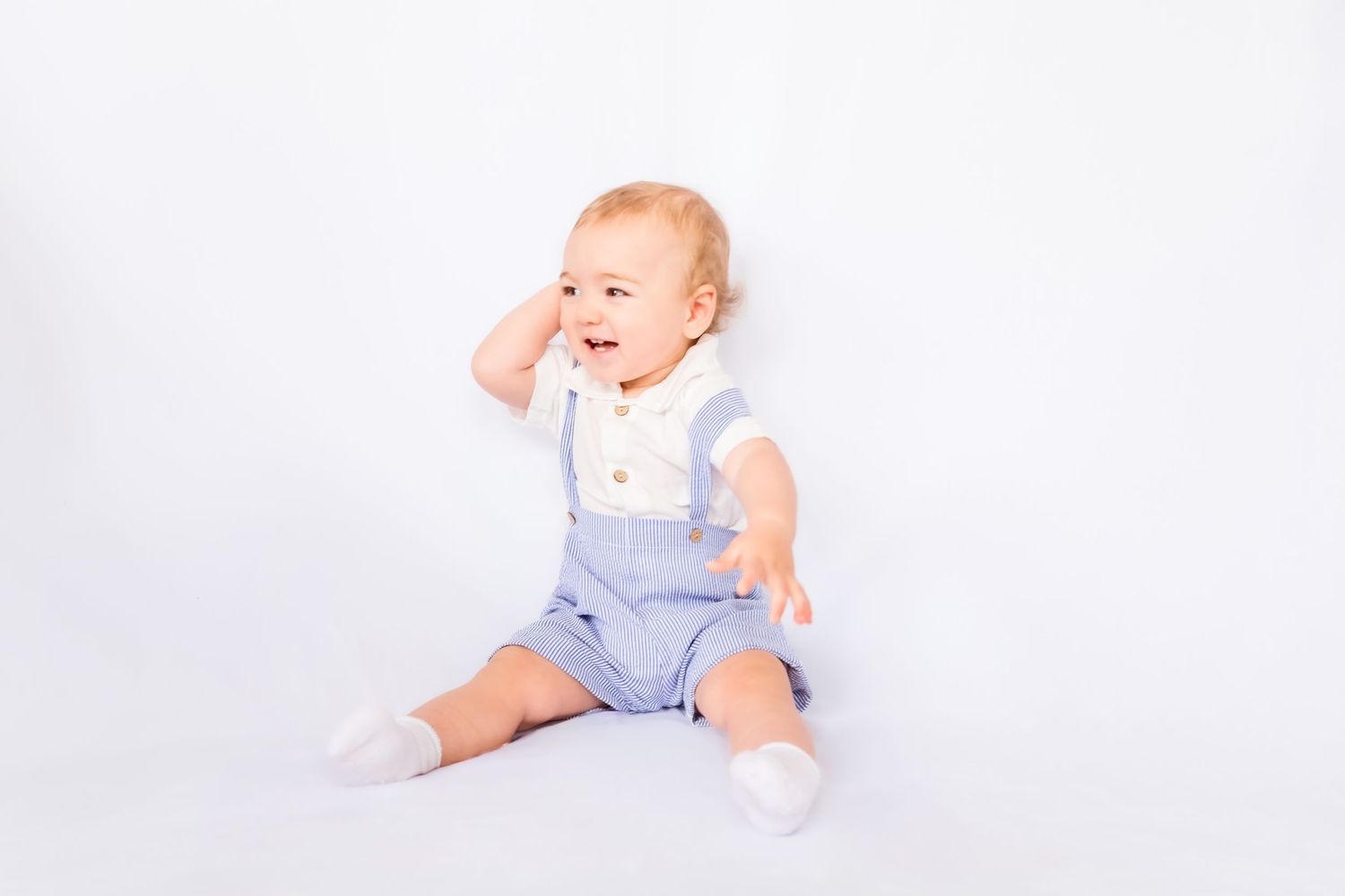 A baby in light blue clothing crawls and plays on a white background in a series of connected photos.