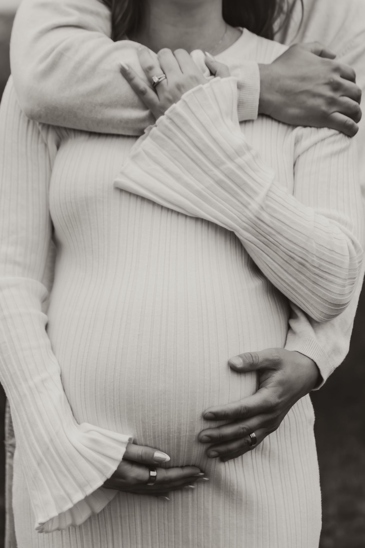 A series of intimate maternity photos showing gentle hands cradling a pregnant belly in a white flowing dress.