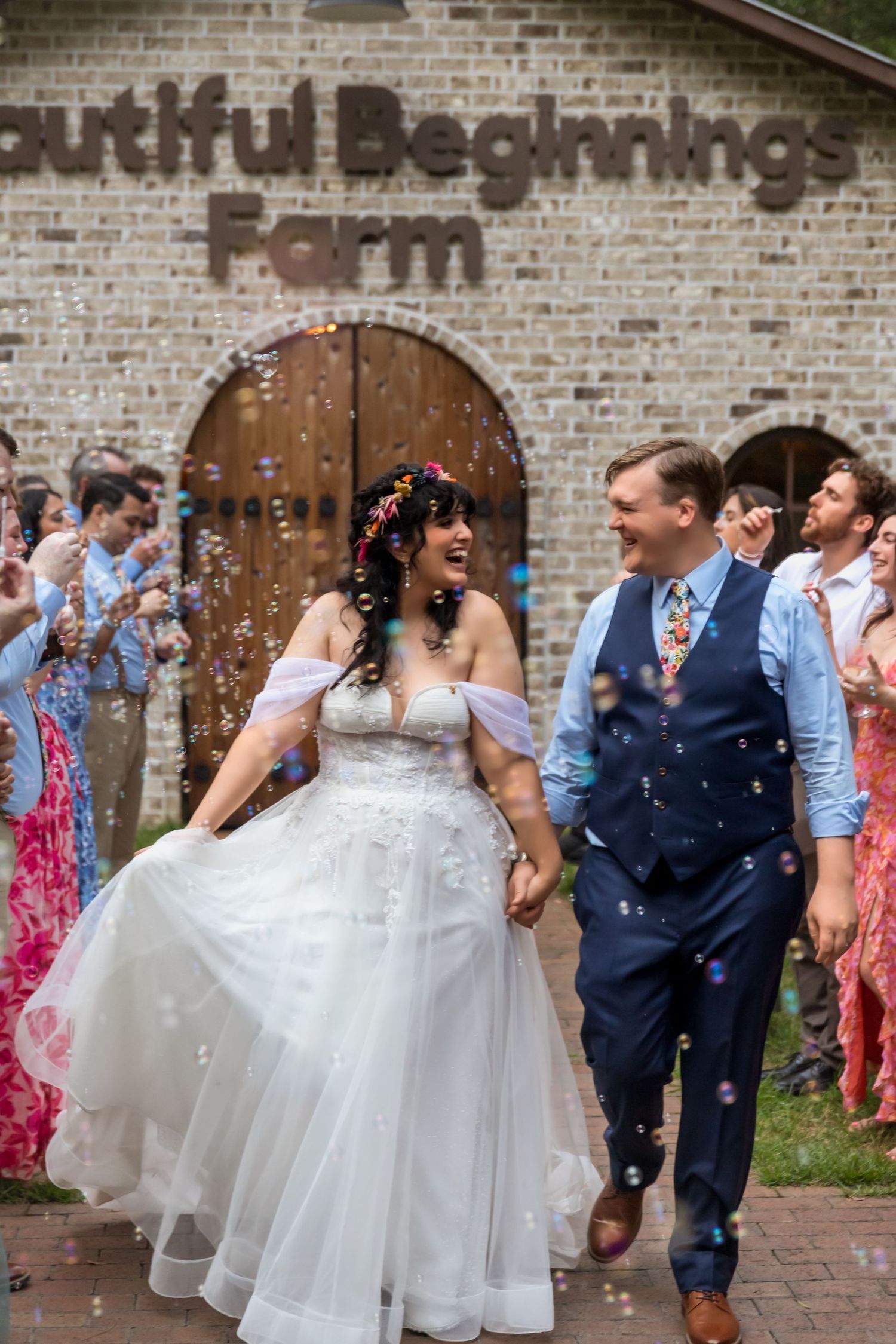 Wedding party celebrates with confetti outside a rustic brick building with arched doorways.
