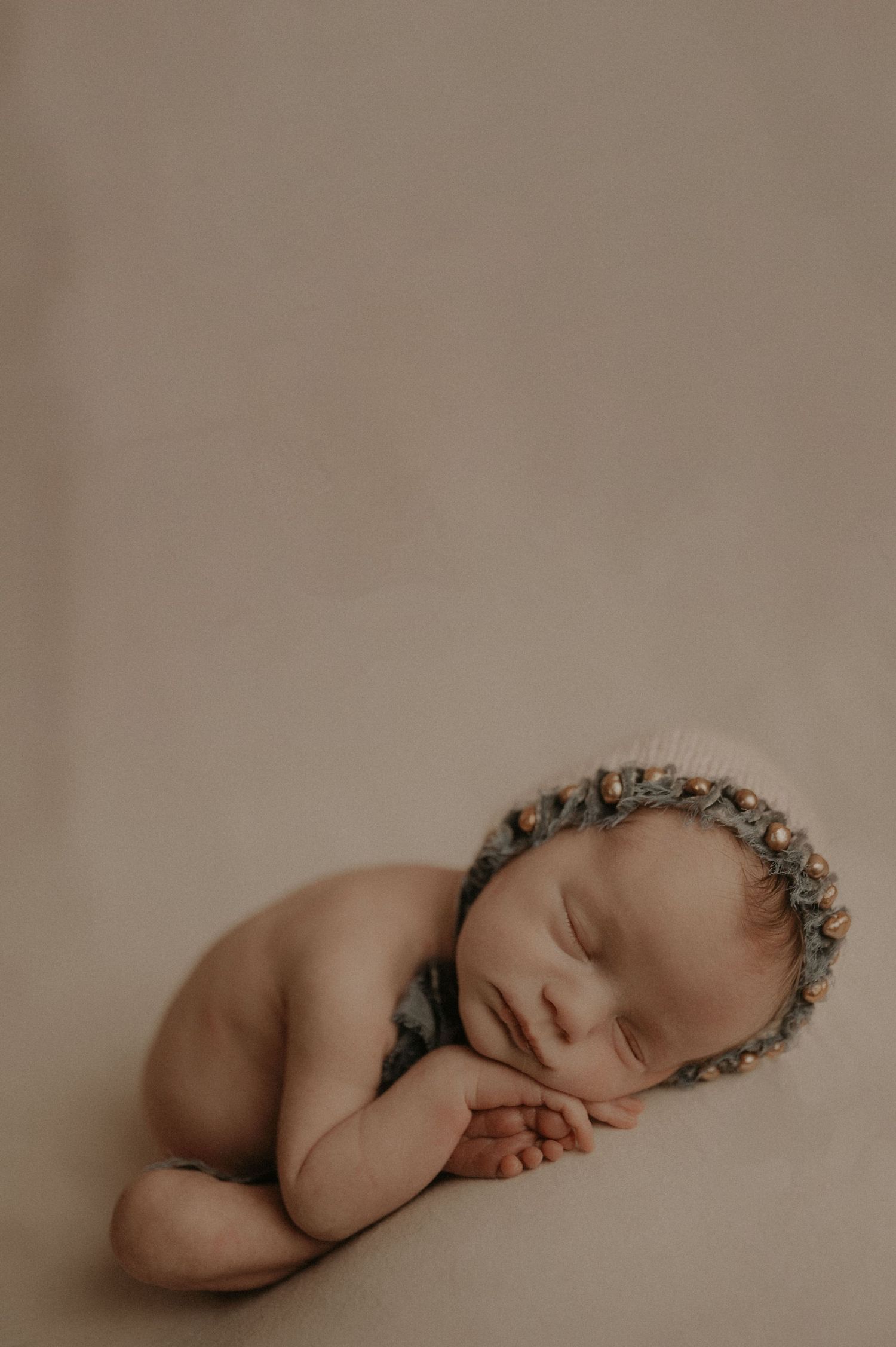 Artistic newborn photography with baby wearing delicate floral headpiece.