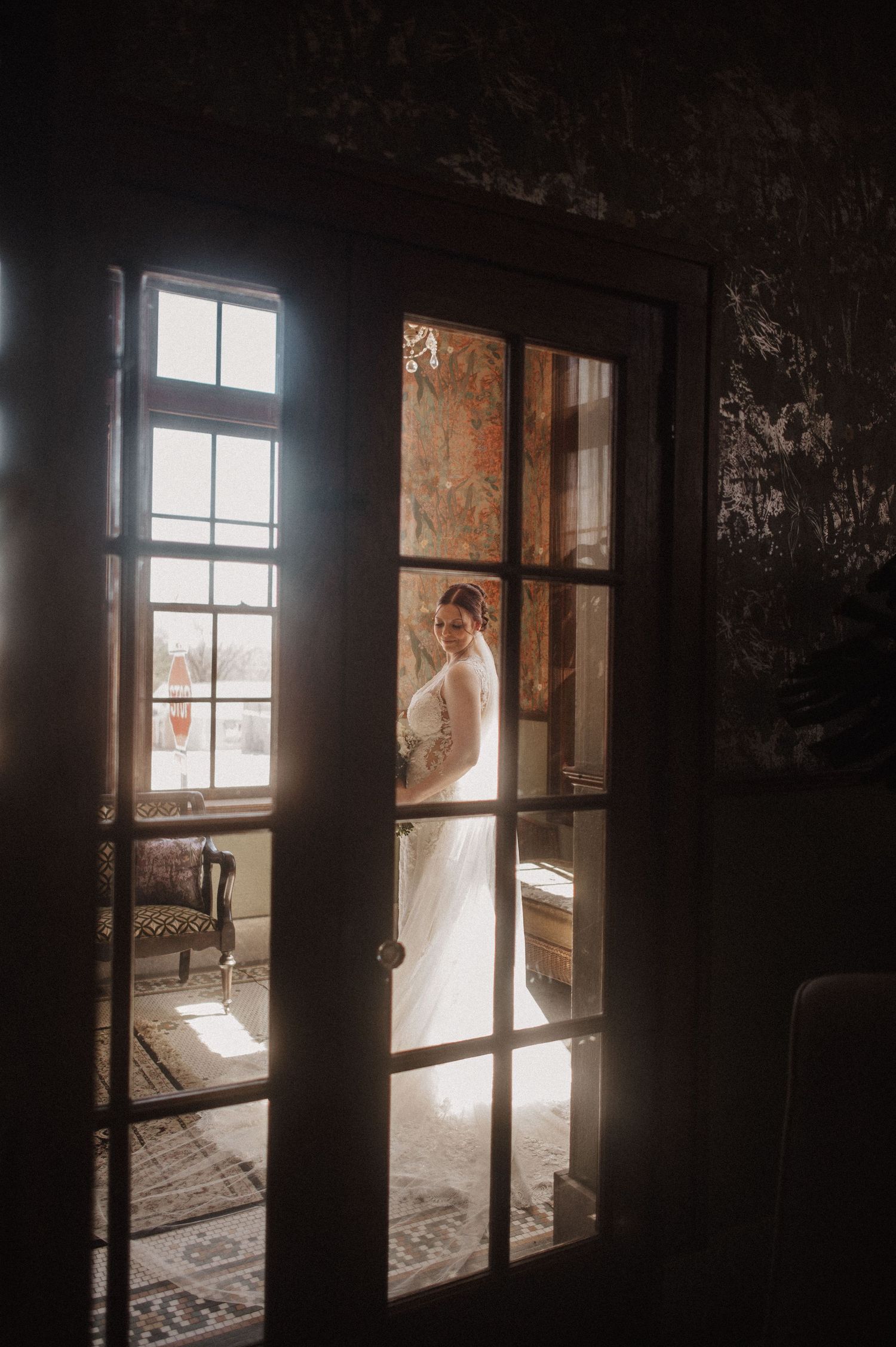 Moody silhouette shots of a bride in a vintage room with dramatic window lighting.