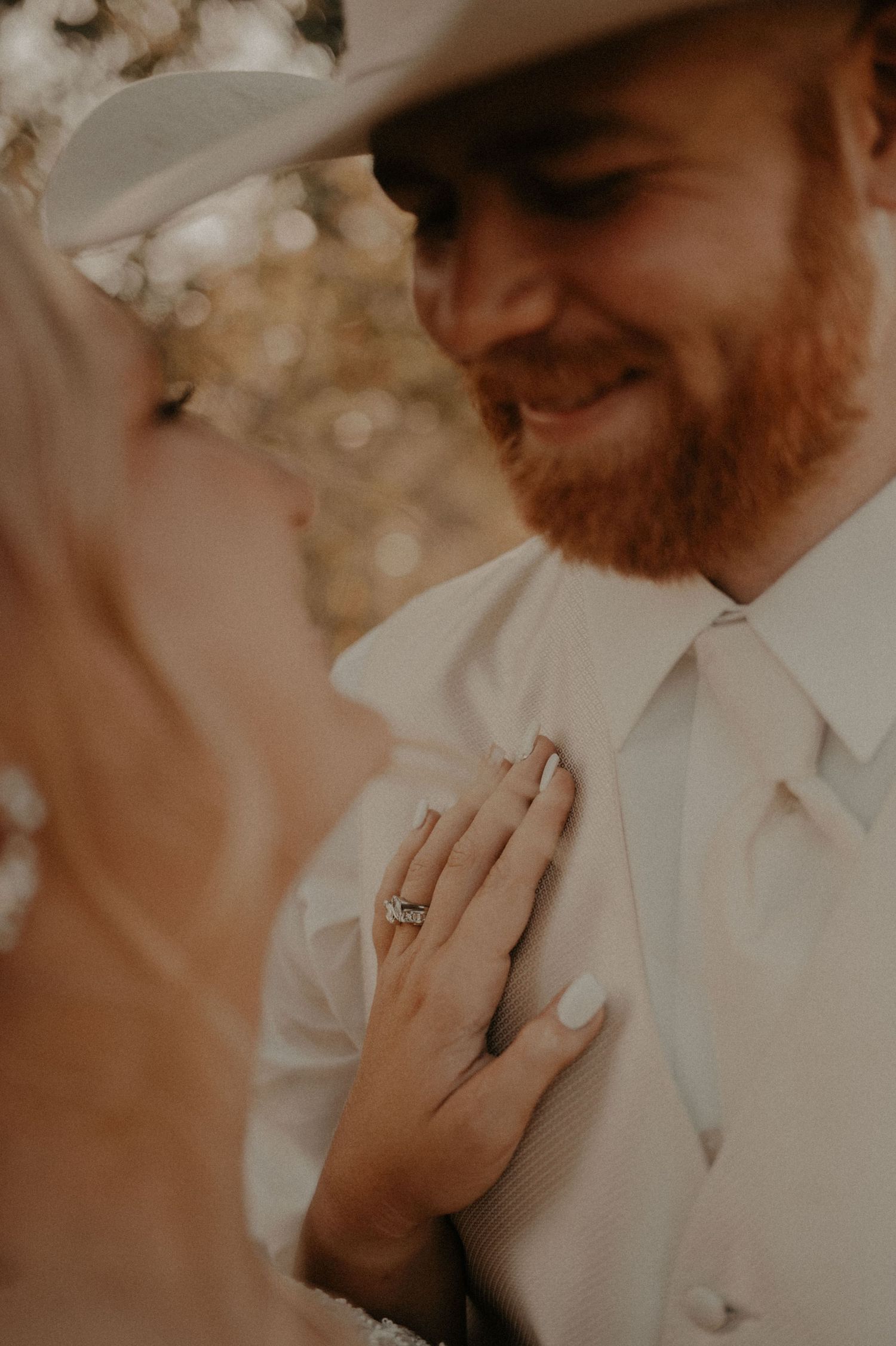 Close-up shot of wedding rings and formal attire in warm natural lighting.