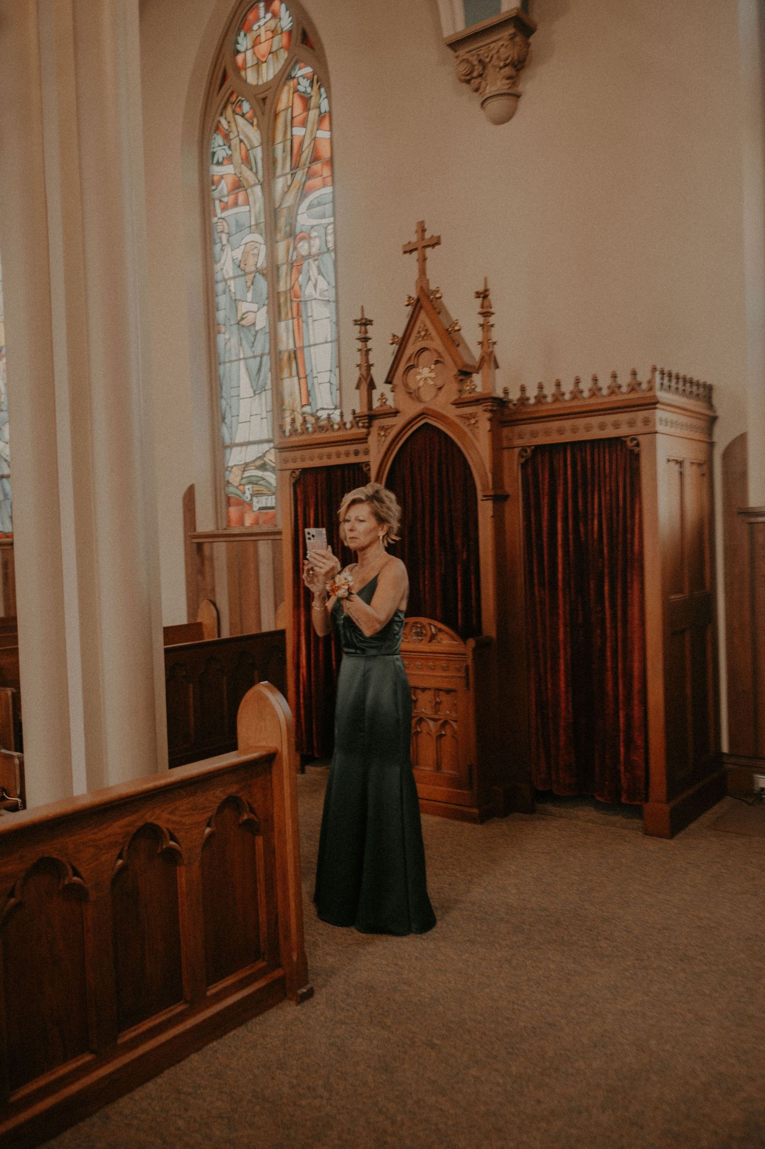 Person in formal attire standing in a church sanctuary with wooden pews and gothic details.