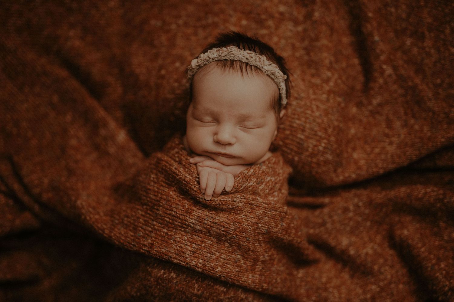 A series of sepia-toned baby photographs arranged in a horizontal collage showing sleeping infants in soft blankets.