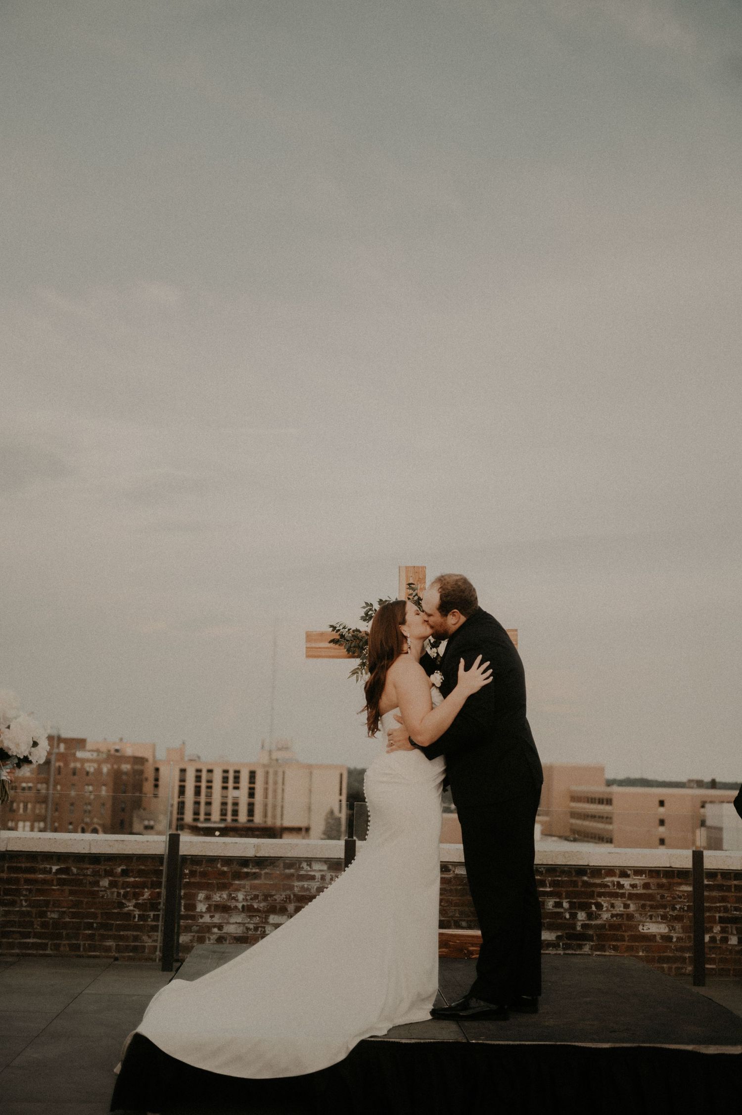 A romantic rooftop wedding portrait with city buildings in the background.