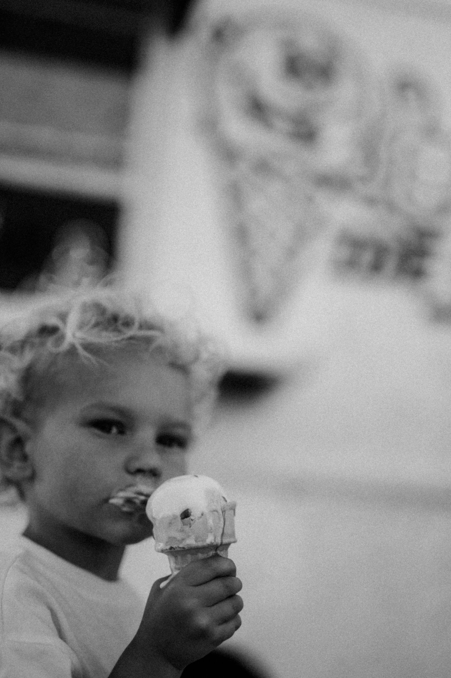 Child enjoying ice cream cone in black and white photography sequence.
