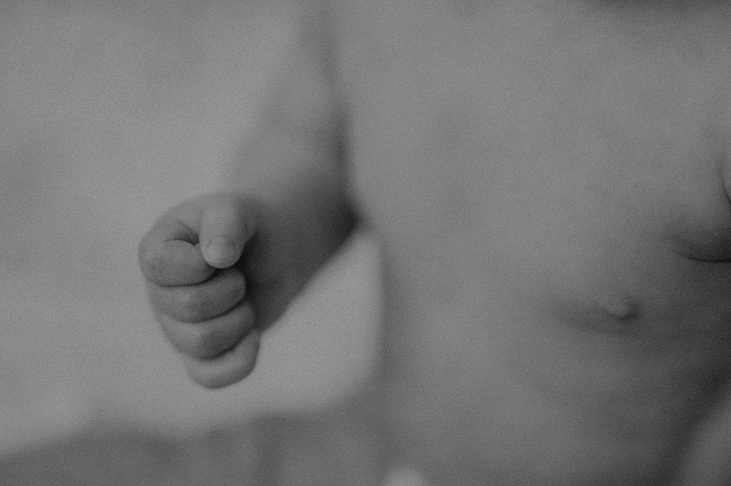 Black and white photograph showing close-up details of human hands and fingers against a blurred background.