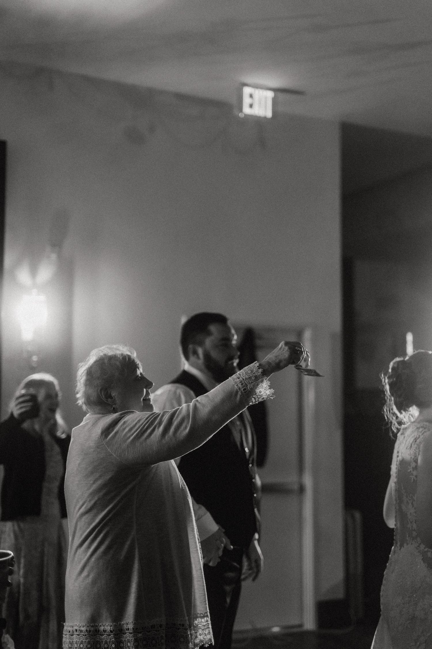Wedding guests performing synchronized dance moves in black and white.