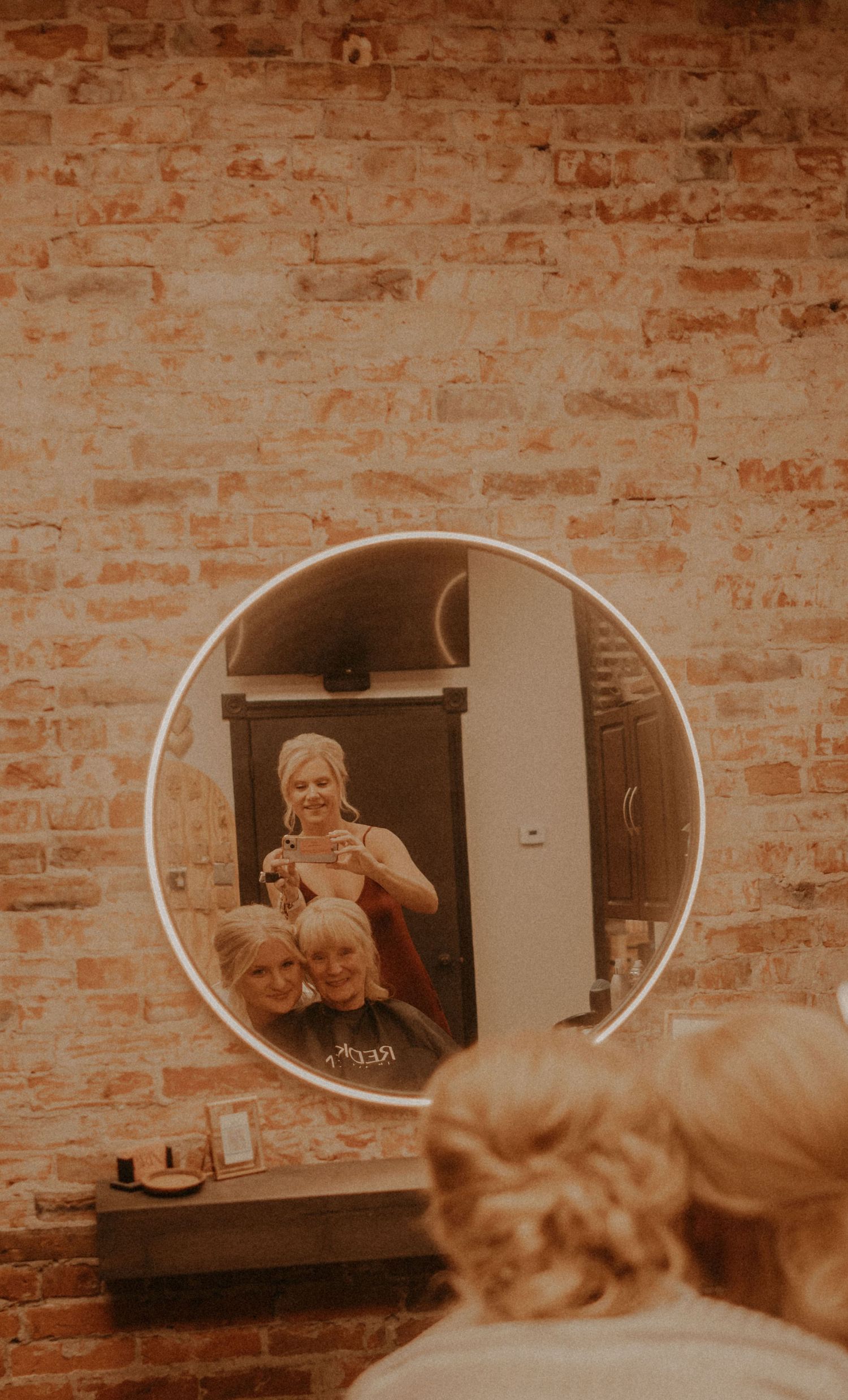 Mirror reflections in a vintage-style dressing area with exposed brick walls.