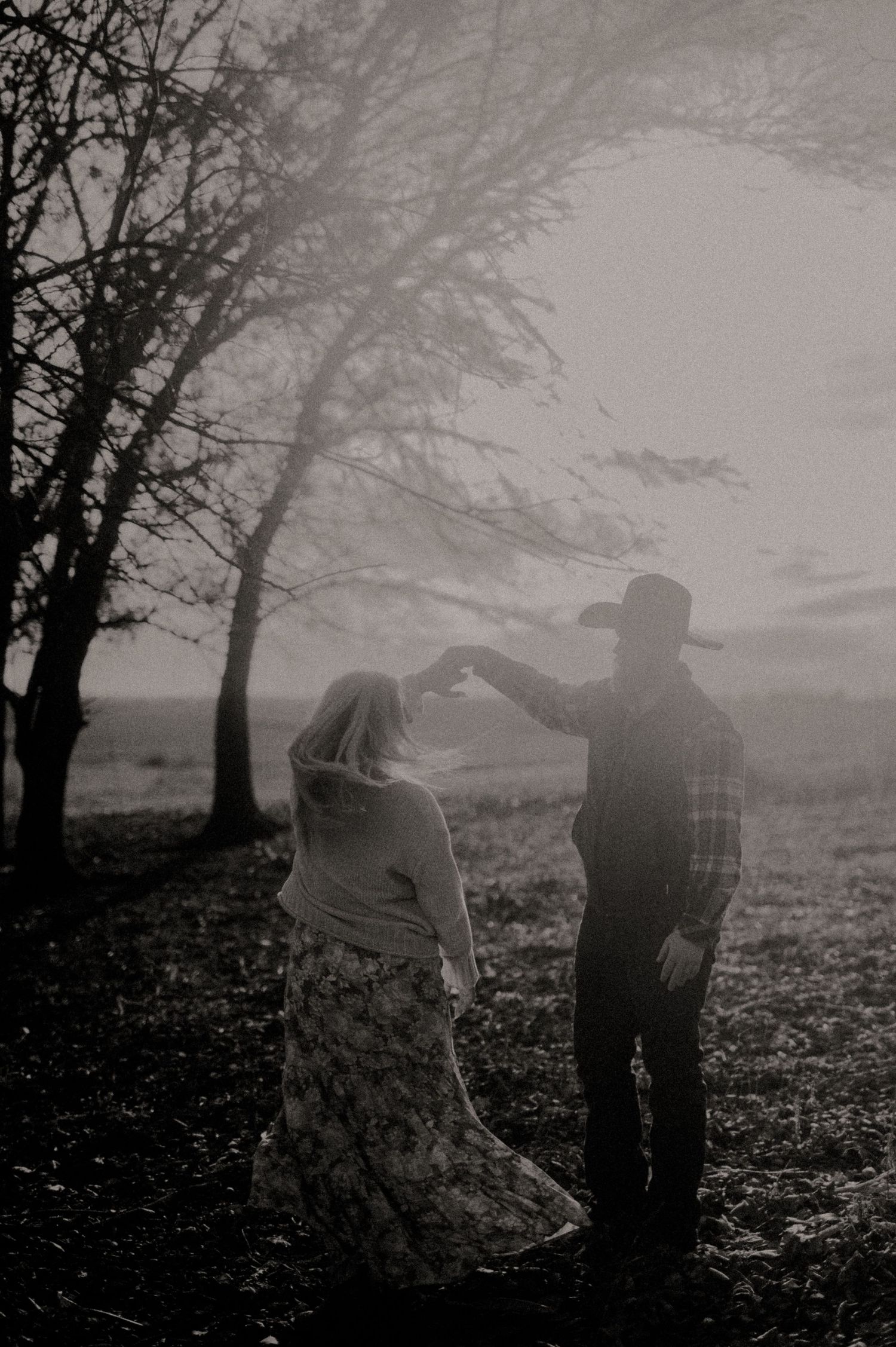 Atmospheric black and white photo of two people in a misty forest setting.