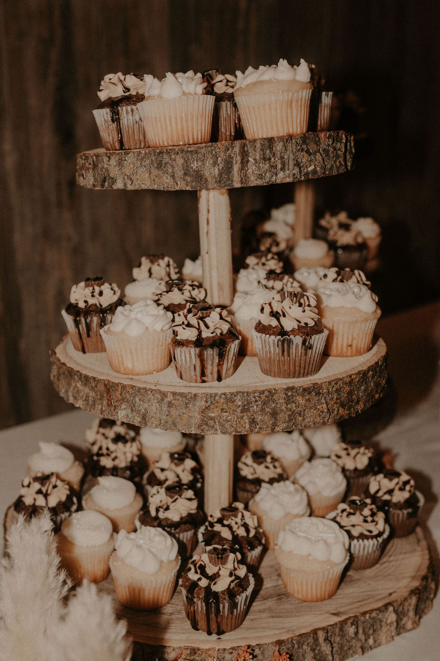 Rustic wedding cupcake display on wooden tiered stands.