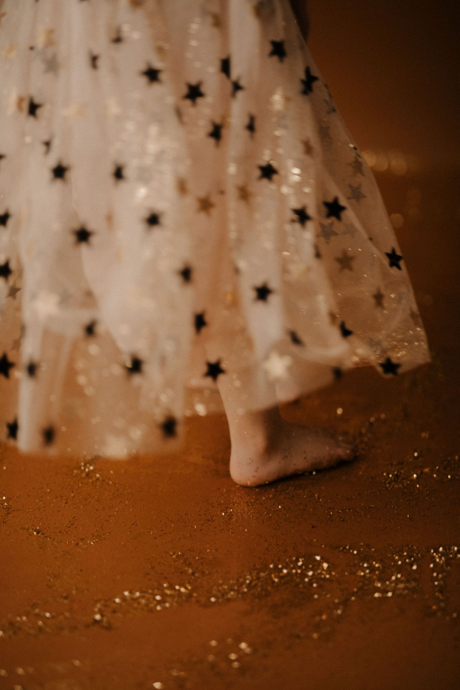 White star-shaped Christmas ornaments with glitter arranged on a brown surface create a festive holiday display.
