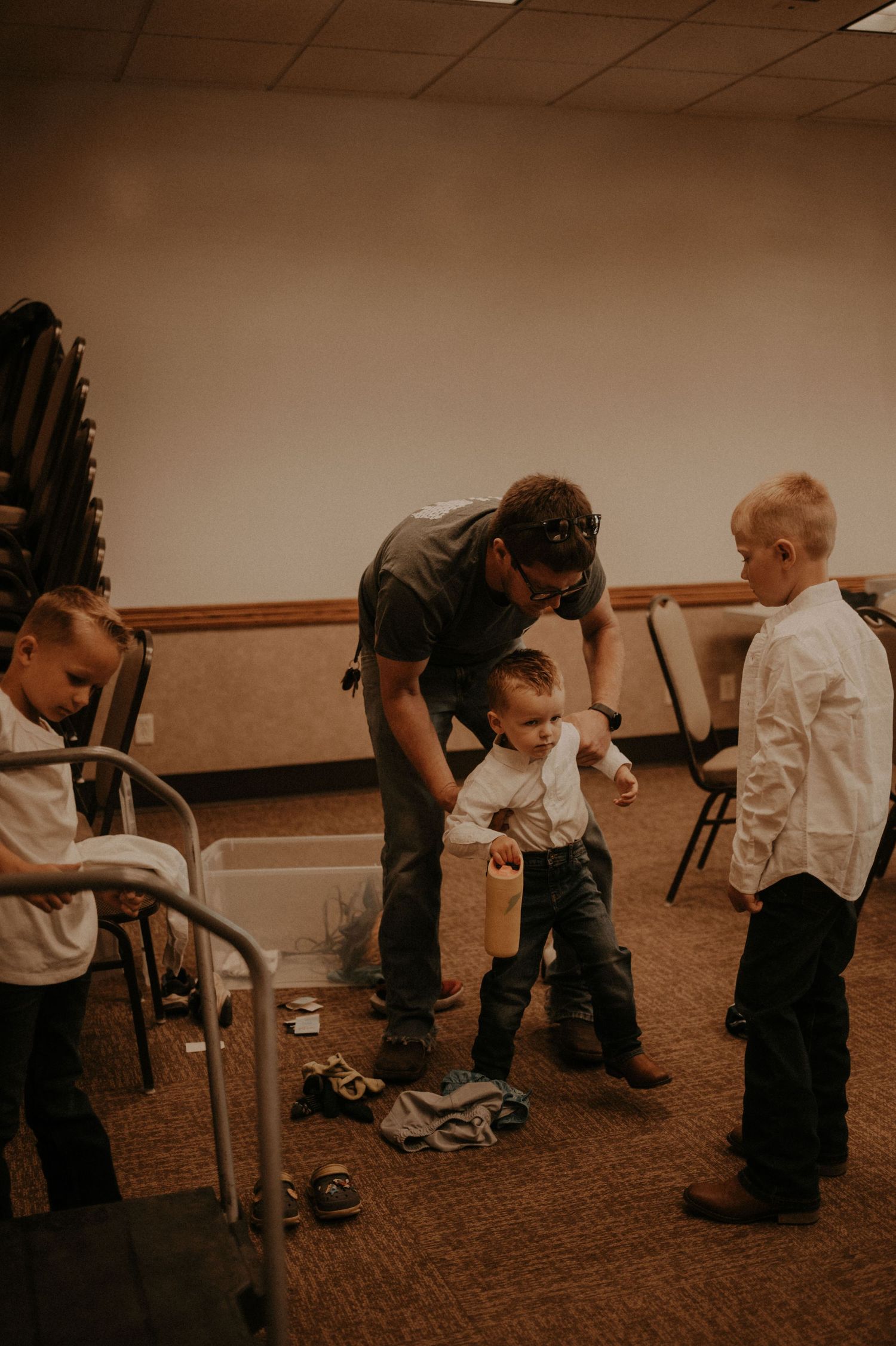 People helping with formal attire preparations in a carpeted room.