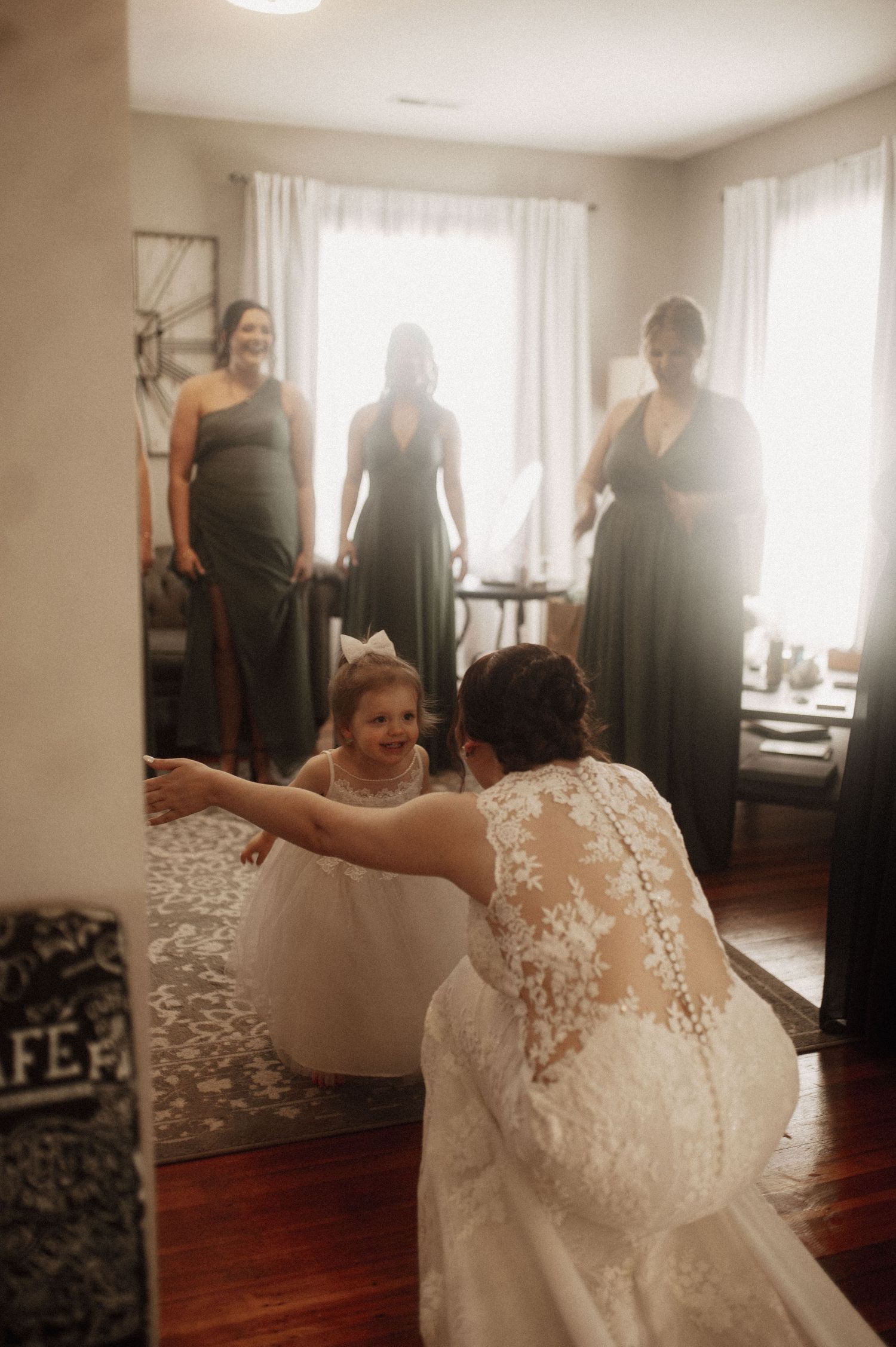 A person in a white lace wedding dress spins joyfully in a room with hardwood floors.