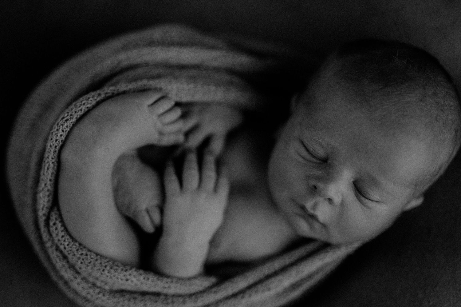 A black and white photo series showing a sleeping baby wrapped in soft blankets in various peaceful poses.