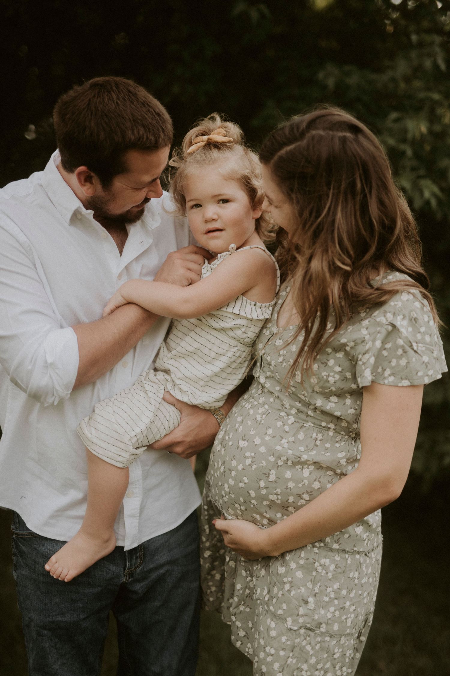 A family shares tender moments together in a series of intimate outdoor portrait photographs.