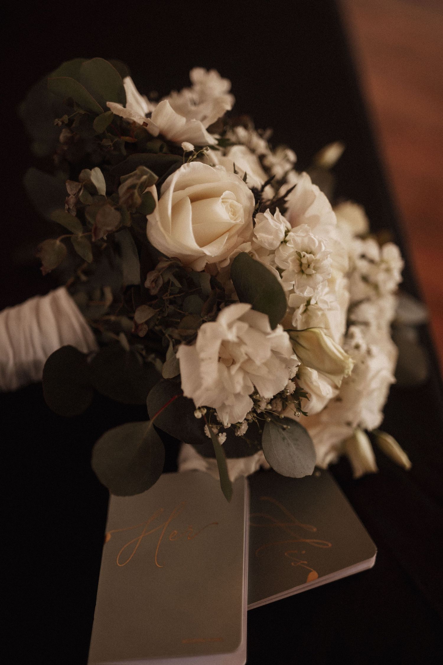 White roses and flowers arranged on books create a romantic moody composition in dark lighting.