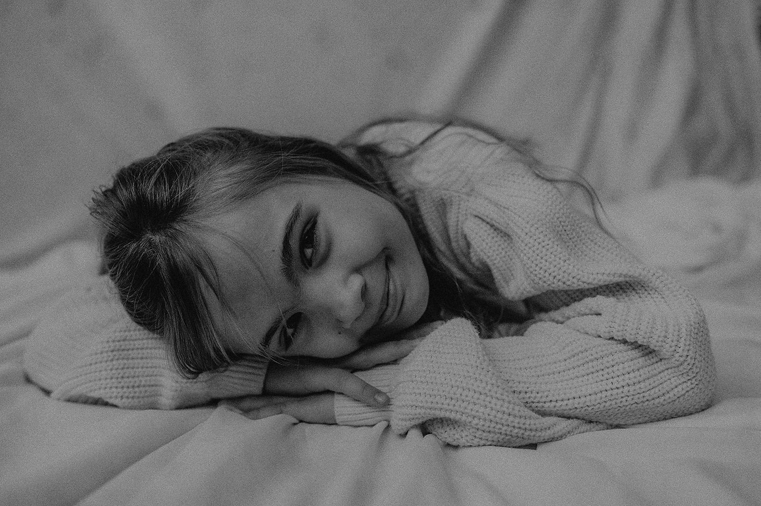 Black and white portrait series showing expressions of joy and playfulness in a ribbed sweater.