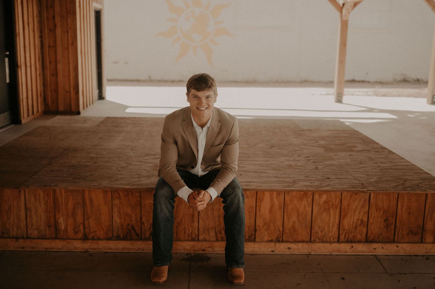 A person sits on wooden steps in a rustic indoor setting with warm lighting and wooden paneled walls.