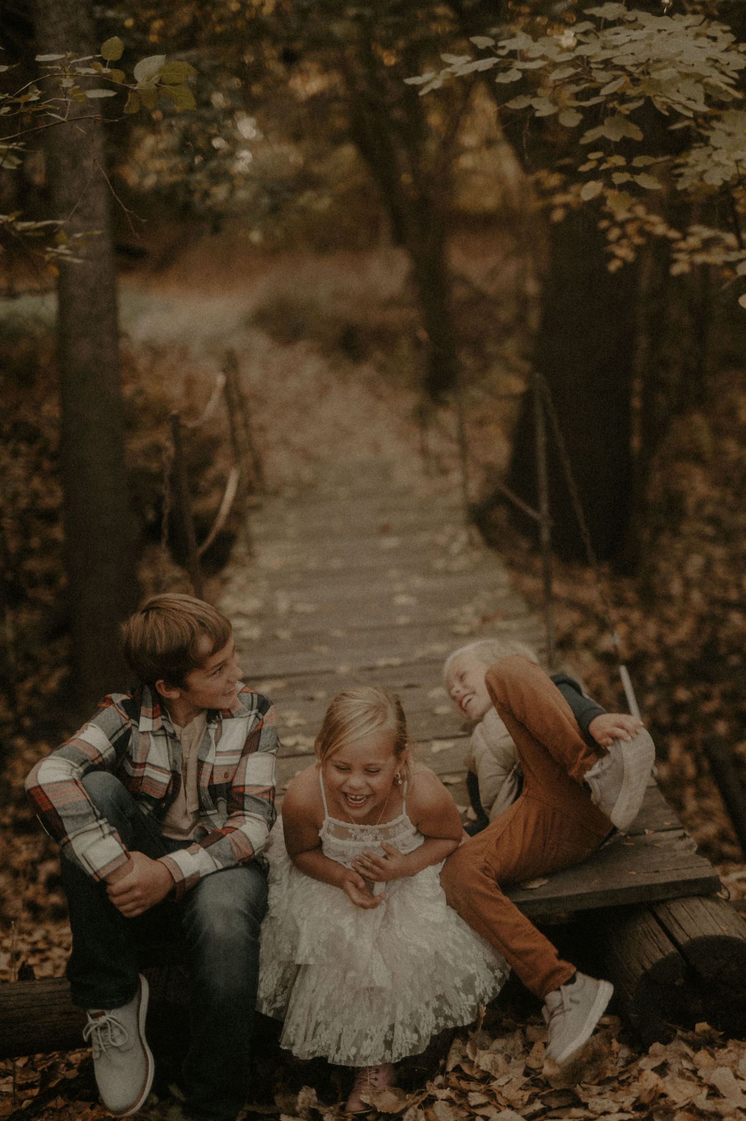 Family members lying in fallen autumn leaves during an outdoor photoshoot.